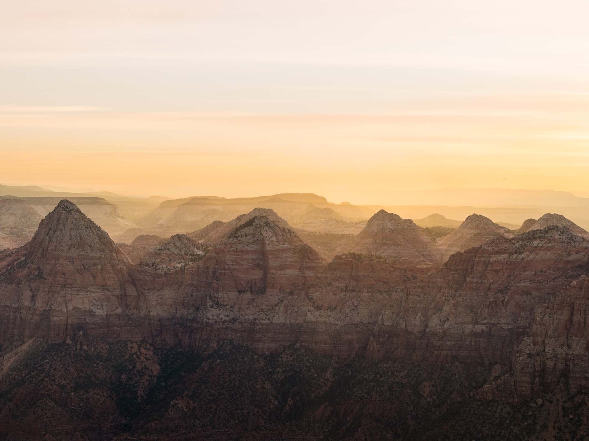 Sunset over the Grand Canyon showing layered rock formations and a hazy sky.