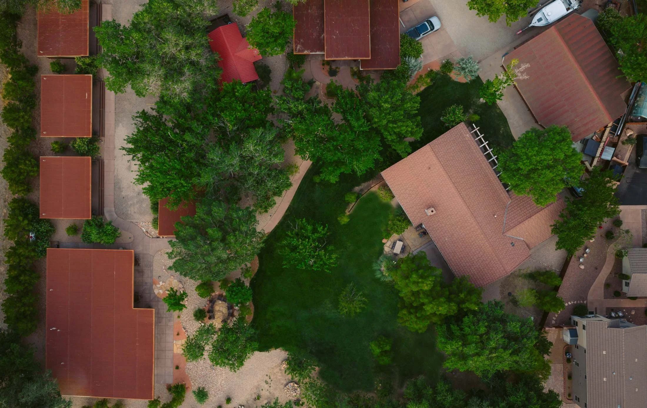 An aerial view of a residential yard with trees, houses, and a lawn. Zion National Park accommodation.
