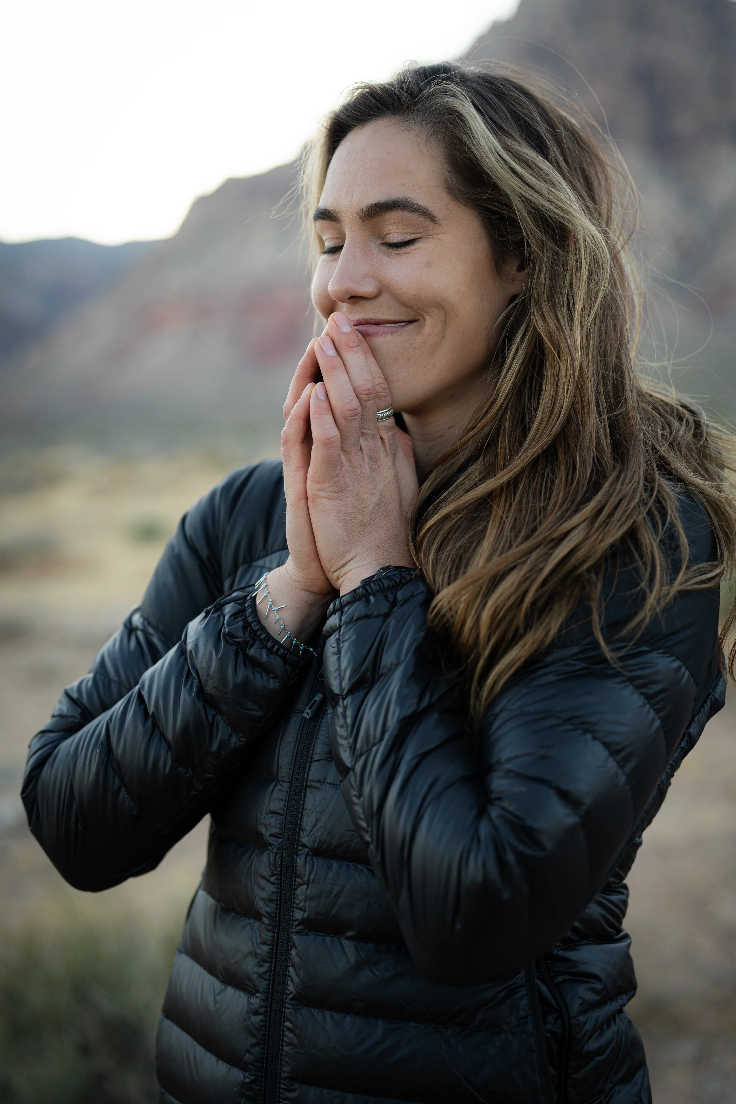 Woman in quiet reflection with hands in prayer pose in a desert landscape near Zion National Park