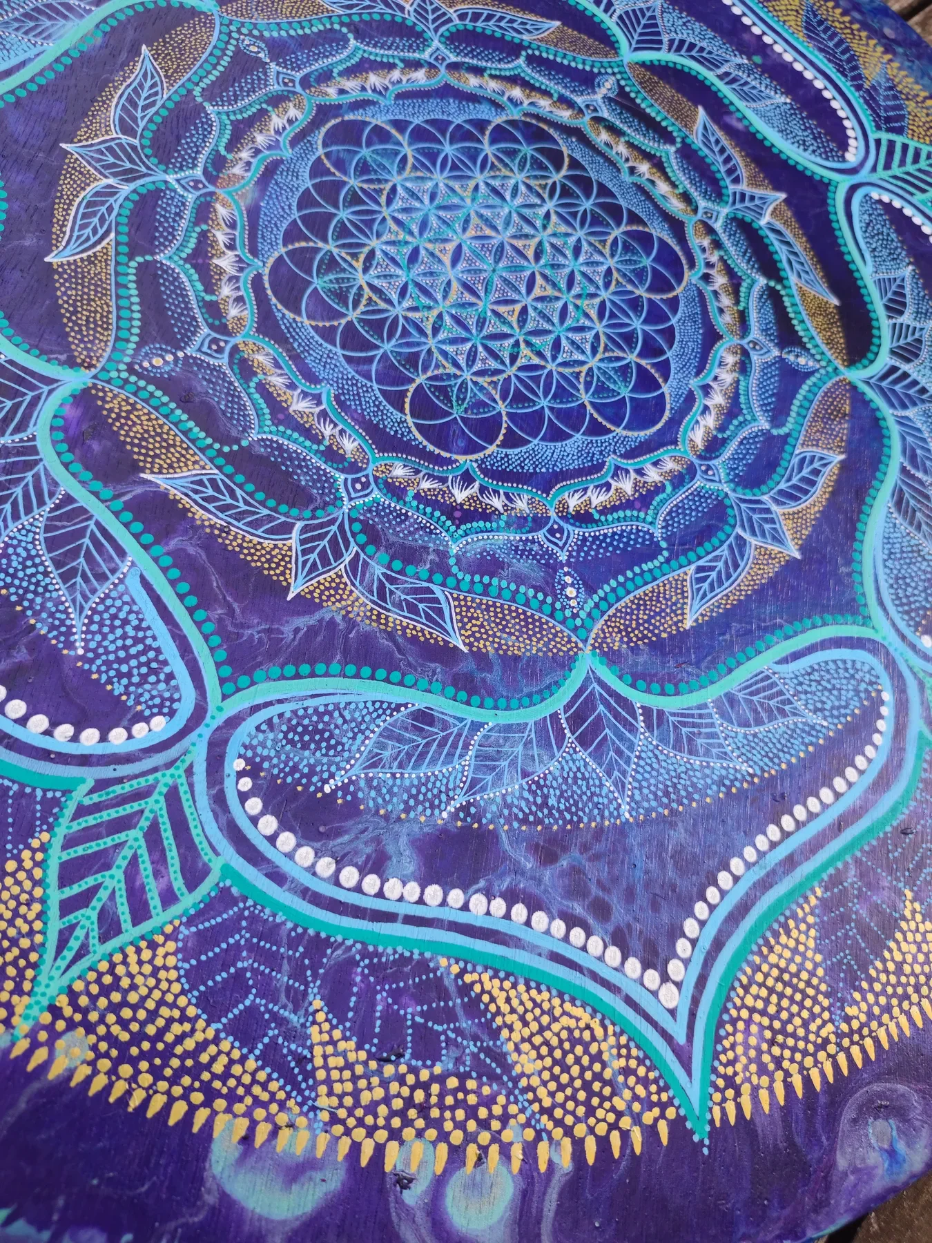 Détails de "Transpersona" oeuvre de Tom Dusauvage. Un mandala coloré avec fleur de vie lumineuses et des motifs floraux et géométriques, sur un fond violet.