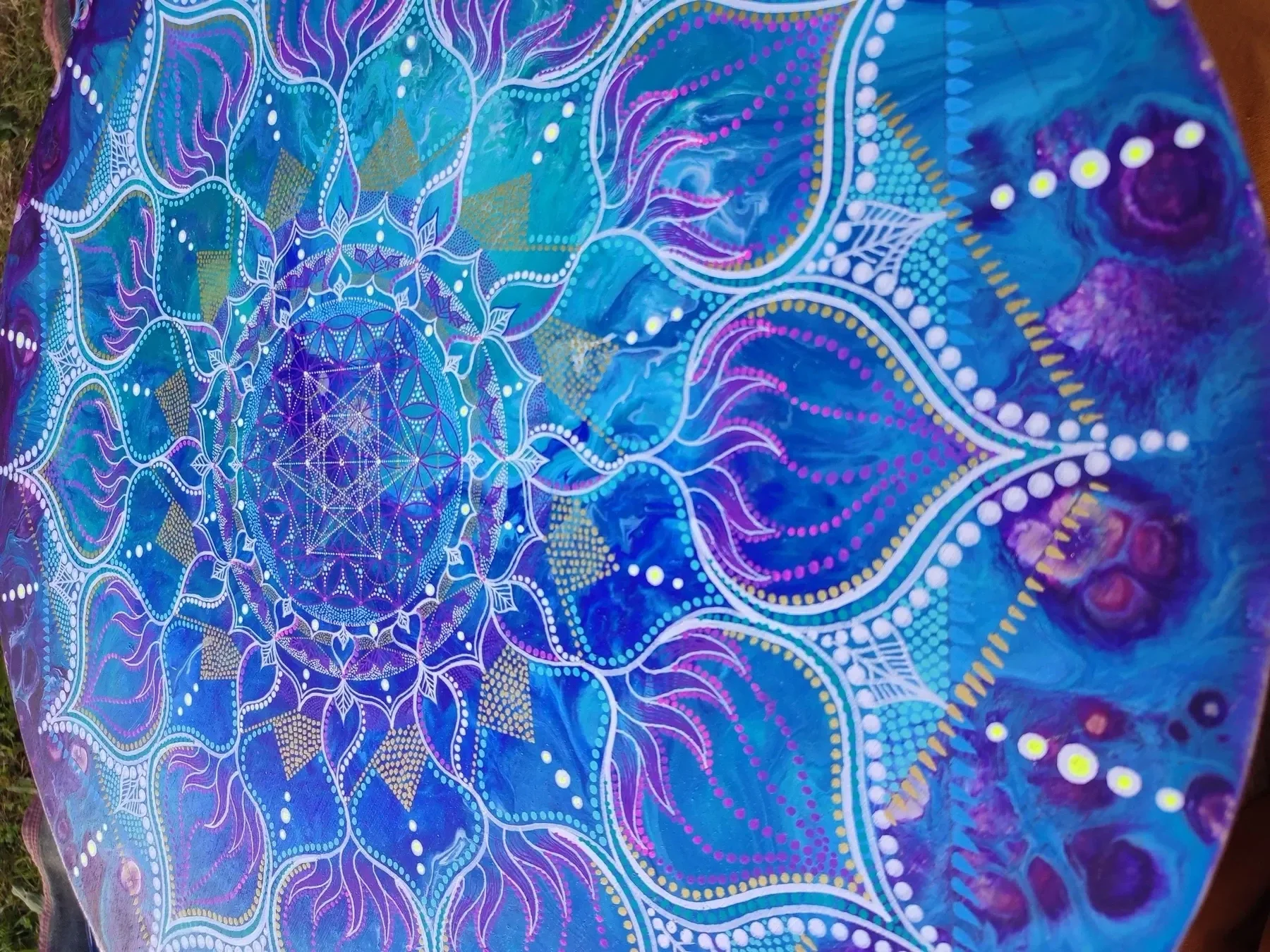 Vue oblique de l'oeuvre "Liquid Sun" Peinture acrylique de géométrie sacrée, mandala aux formes symétriques et fluides, développant la fleur de vie et le cube de Metatron, points et lignes en tons de bleu, violet, blanc et orréalisée par Tom Dusauvag