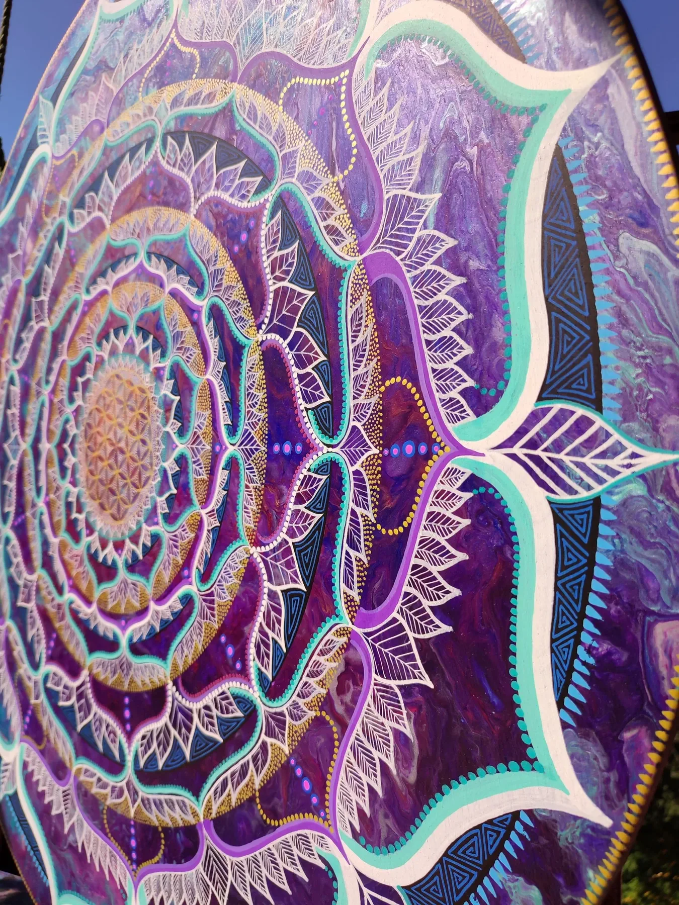 Vue oblique de l'oeuvre "Alchimystic" mandala de géométrie sacrée explorant les structures de la fleur de vie au centre de motifs organique et symétrique, coloré de violé et or, peinte par Tom Dusauvage.