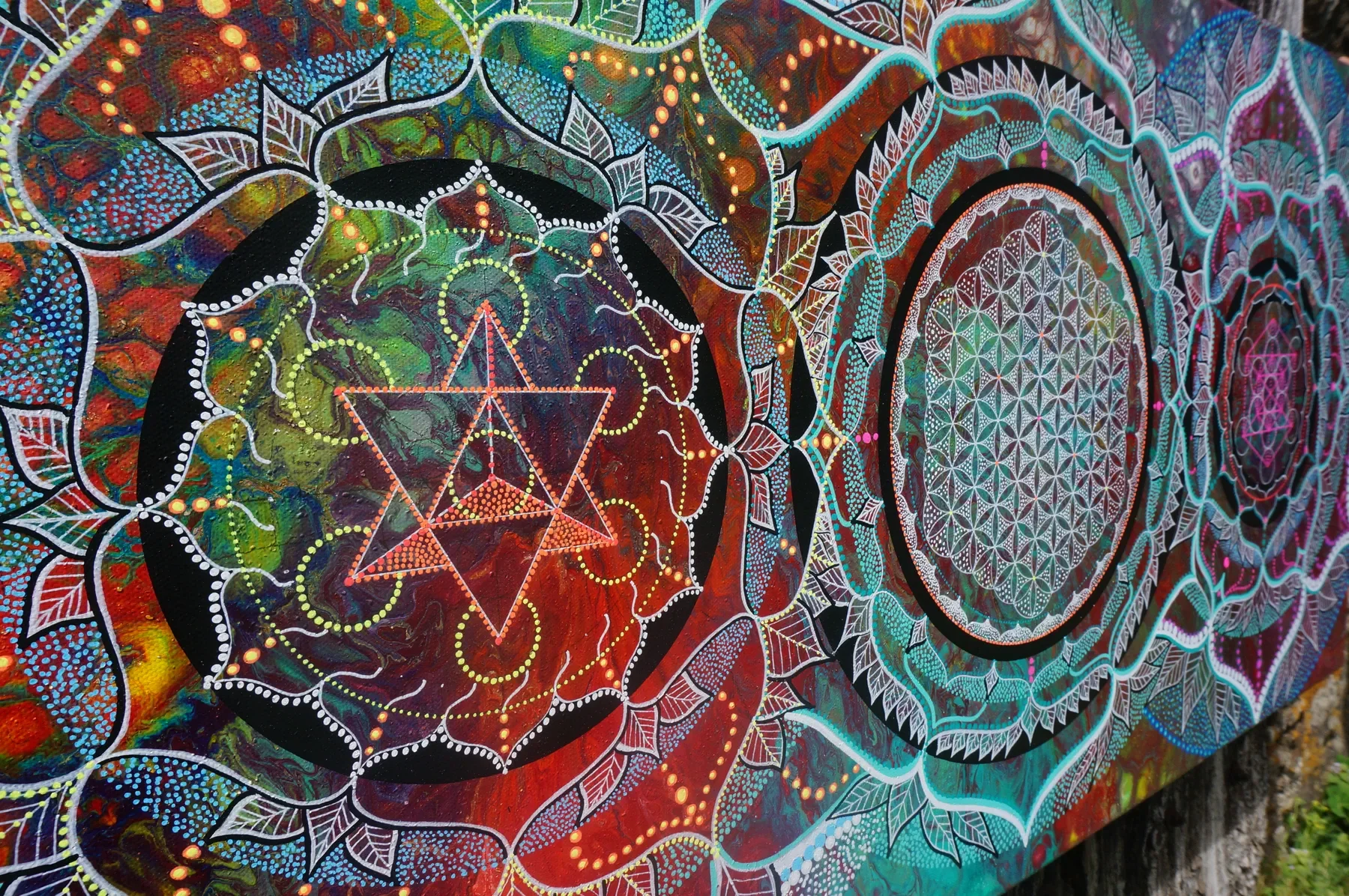 Détails de l'oeuvre "Evolution"  de Tom Dusauvage, artiste visionnaire. Design de géométrie sacrée coloré avec 3 mandala intriquée, déclinaison de la fleur de vie vers la merkaba, des fleurs et des feuilles, en couleurs vives, tons chauds et détaillé