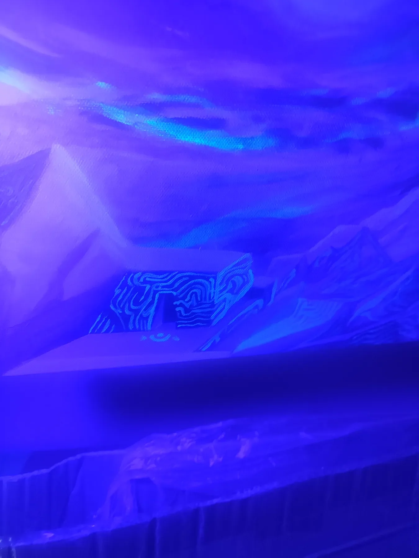 Détail sous lumière UV de "Exoplanet" Œuvre abstraite visionnaire représentant des paysages montagneux oniriques, et un temple aux motifs fluorescent . Acrylique sur toile par Tom Dusauvage.