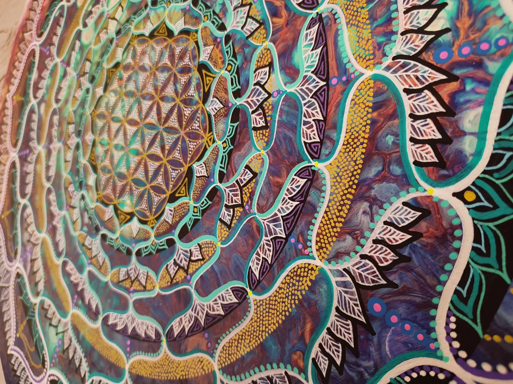 Vue oblique détaillée de l'oeuvre "Ecstatic Trance" Mandala coloré de l'artiste visionnaire Tom Dusauvage, utilisant une fleur de vie aux couleurs vives comme le violet, le vert, le jaune et le rouge, avec des détails complexes et symétriques.