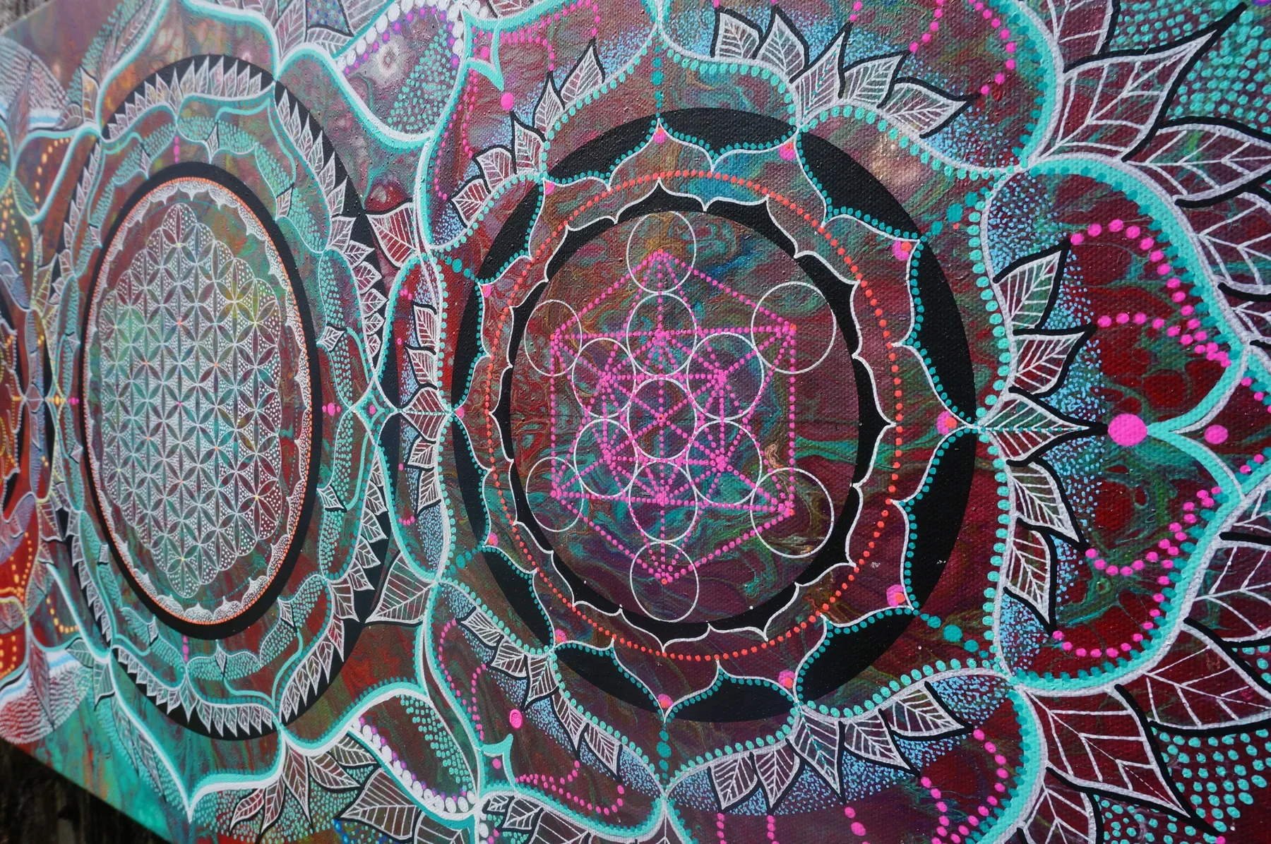 Détails du cube de métatron dans l'oeuvre "Evolution" de Tom Dusauvage, artiste visionnaire. Design de géométrie sacrée coloré avec 3 mandala intriquée avec des fleurs et des feuilles, en couleurs vives, tons turquoises et rose fluo