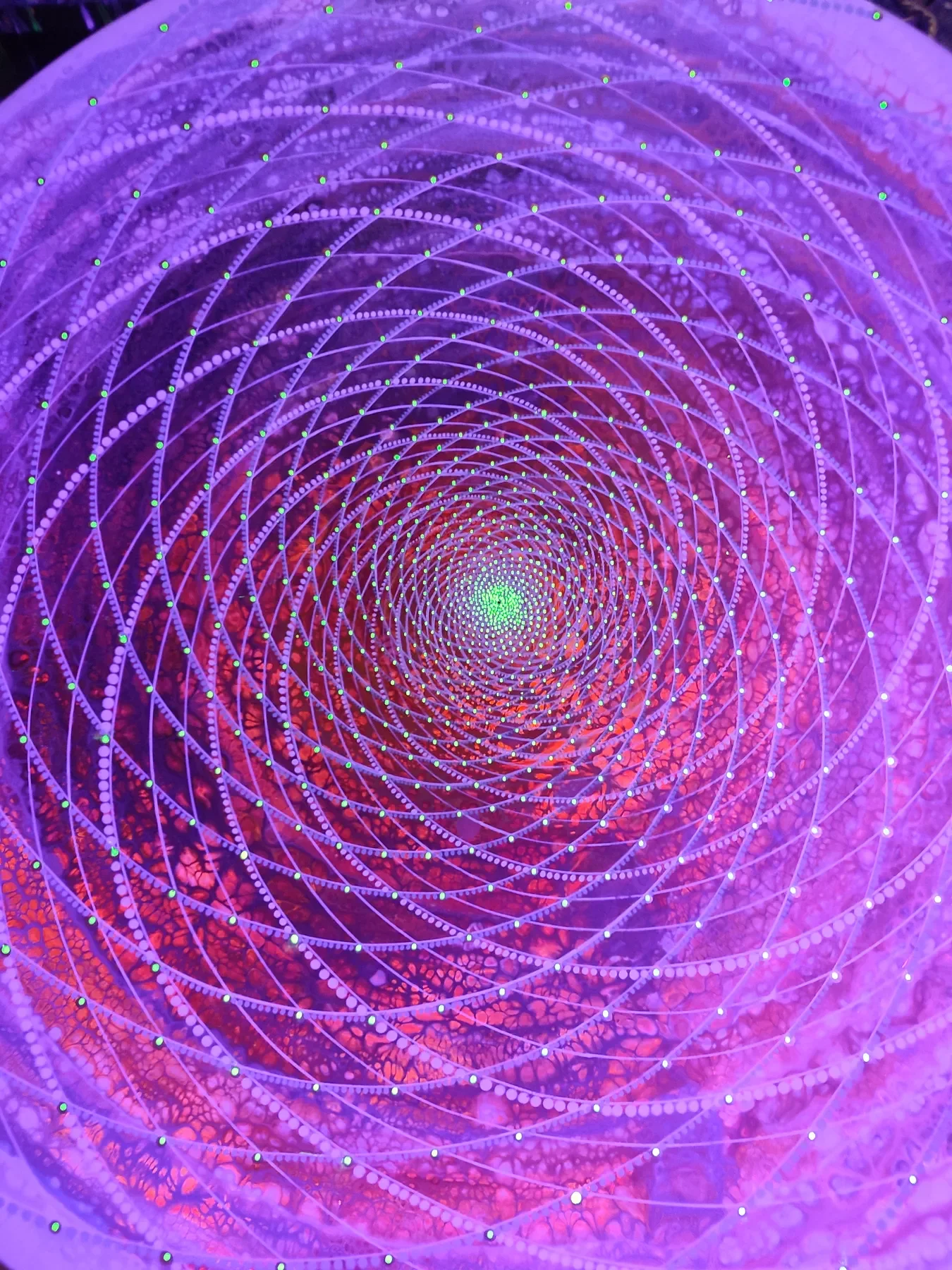Détail sous UV de "Galactis" par Tom Dusauvage. Un vortex coloré formant des motifs en dégradé de couleurs chaudes évoquant un effet hypnotique ou une galaxie