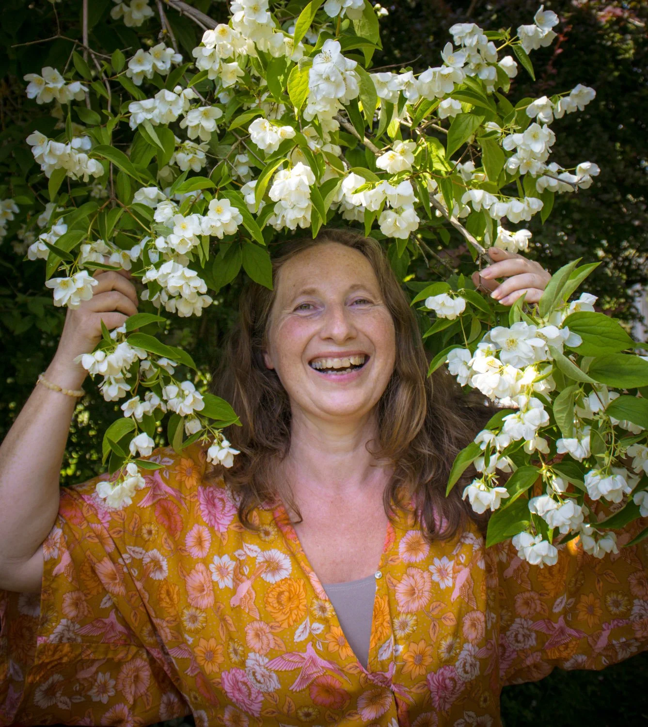 Kvinne i hagen holder duftskjærsmin og dufter, i et øyeblikk med yoga og meditasjon ute