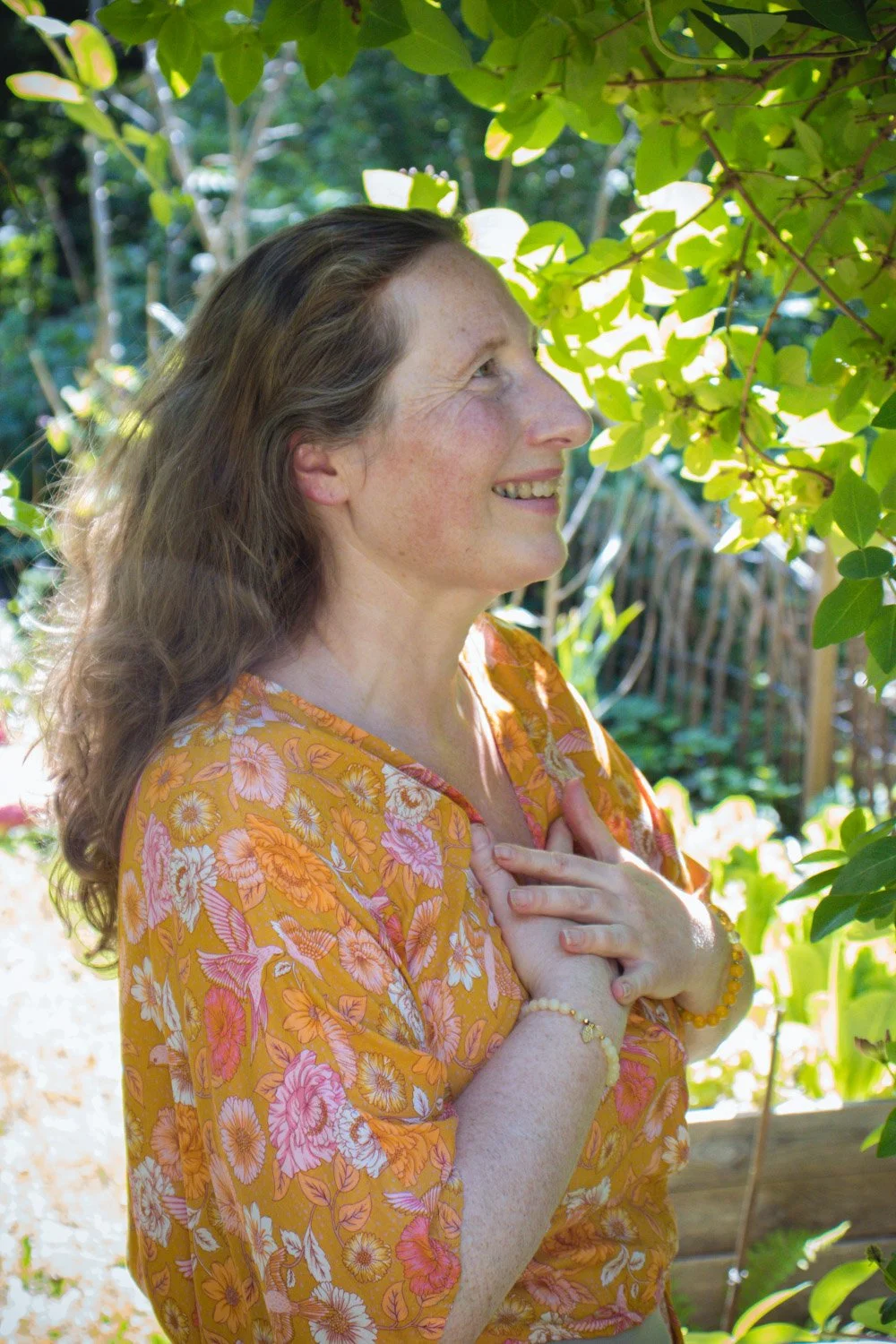 Kvinne står rolig i hagen med hendene på hjertet og gjør mindfulness for indre ro