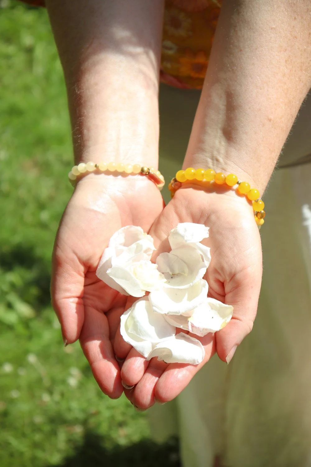 Hender som holder blomster i en grønn hage under rolig meditasjon