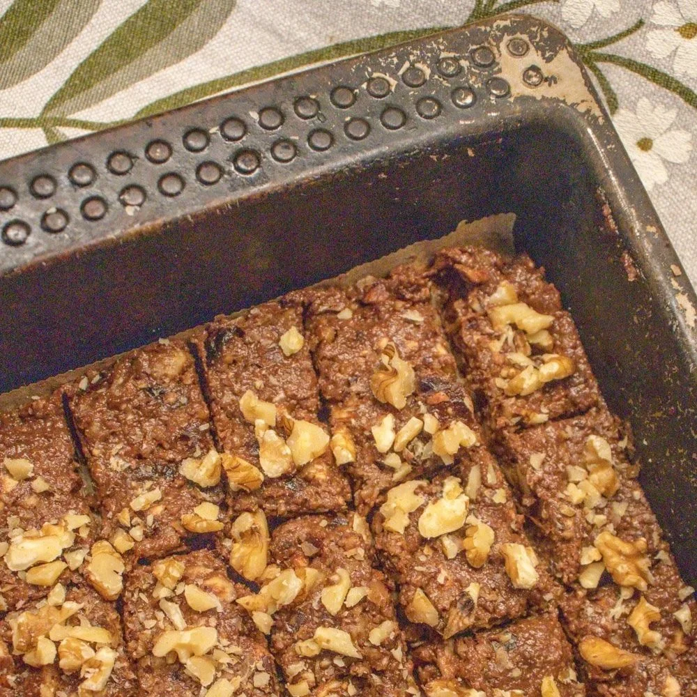 Seig nøttekladdekake uten steking med kakao og nøtter, skåret i små biter.