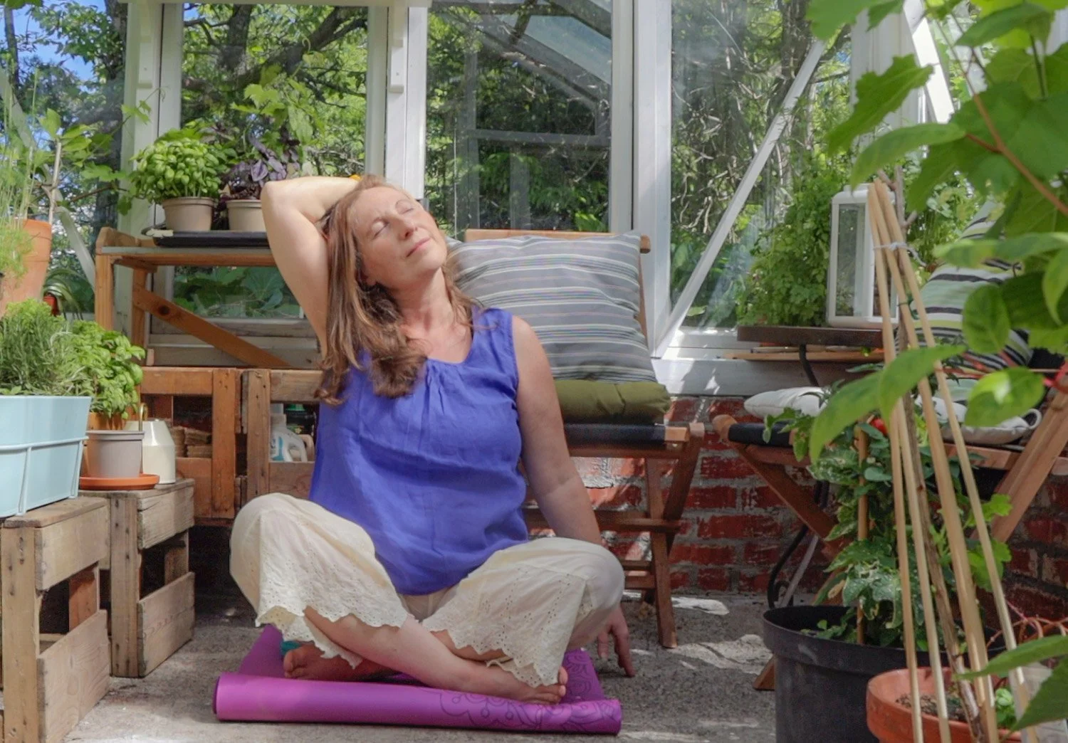En kvinne gjør yoga for nakke og skuldre i drivhus