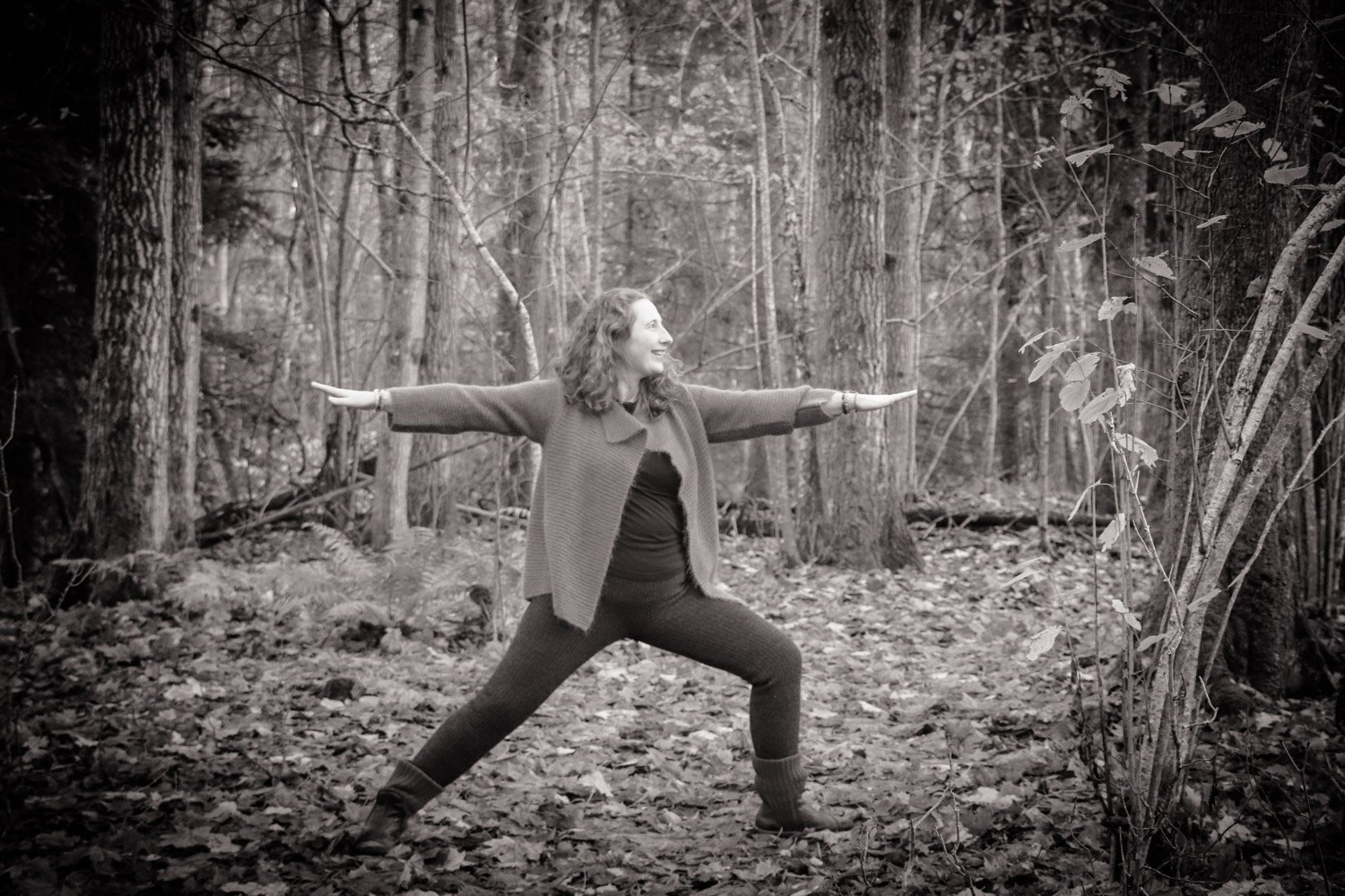 Kvinne gjør myk yoga i skogen, omgitt av trær og rolig natur. Rolig yogapraksis med pust, tilstedeværelse og indre balanse.