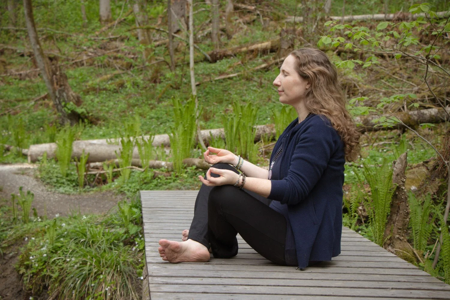 Kvinne som mediterer i skogen om våren