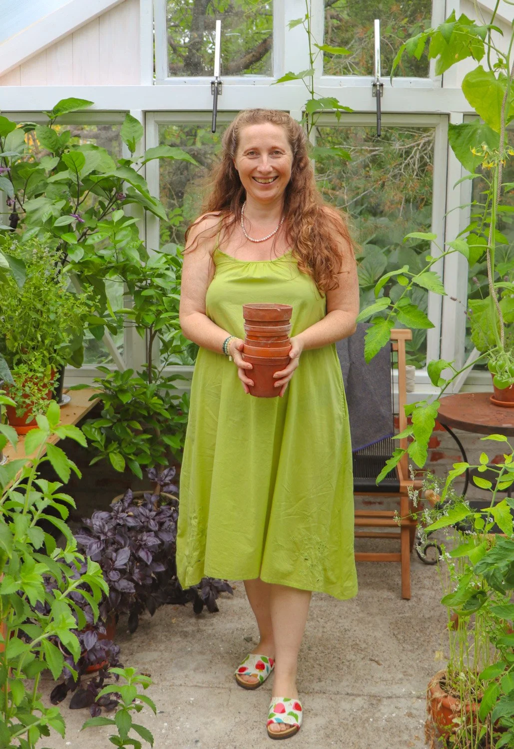 Kvinne med plantepotter i drivhuset