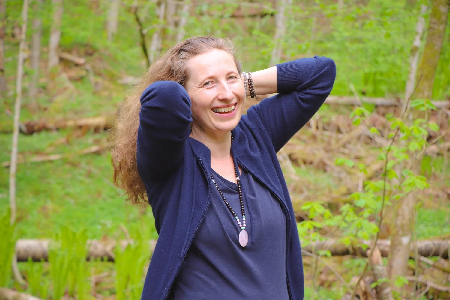 Kvinne gjør myk yoga ute i skogen for å mykne kroppen og redusere stivhet. Rolig yogapraksis med pust og naturkontakt