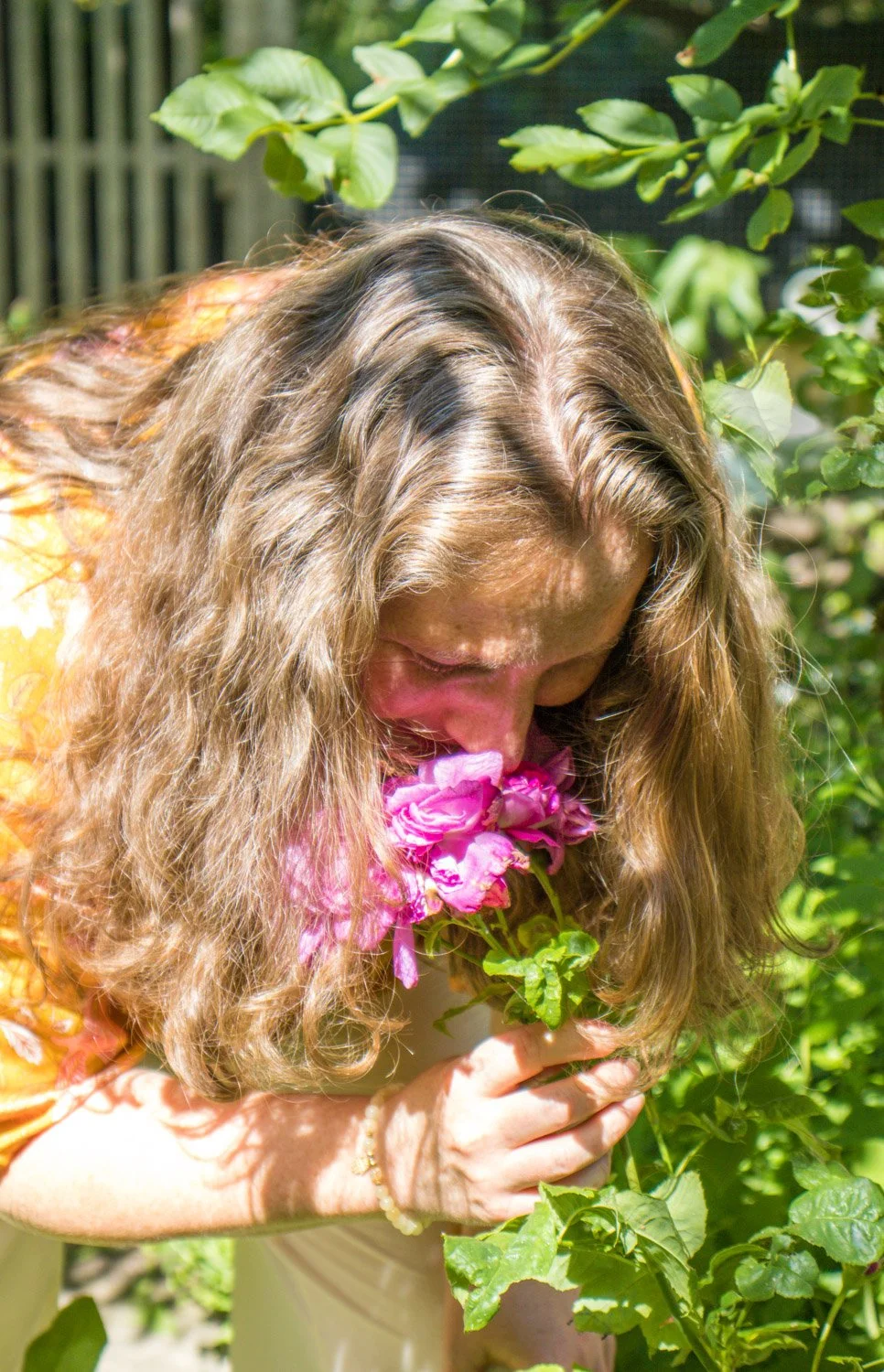 En kvinne dufter på en rose som rosemeditasjon