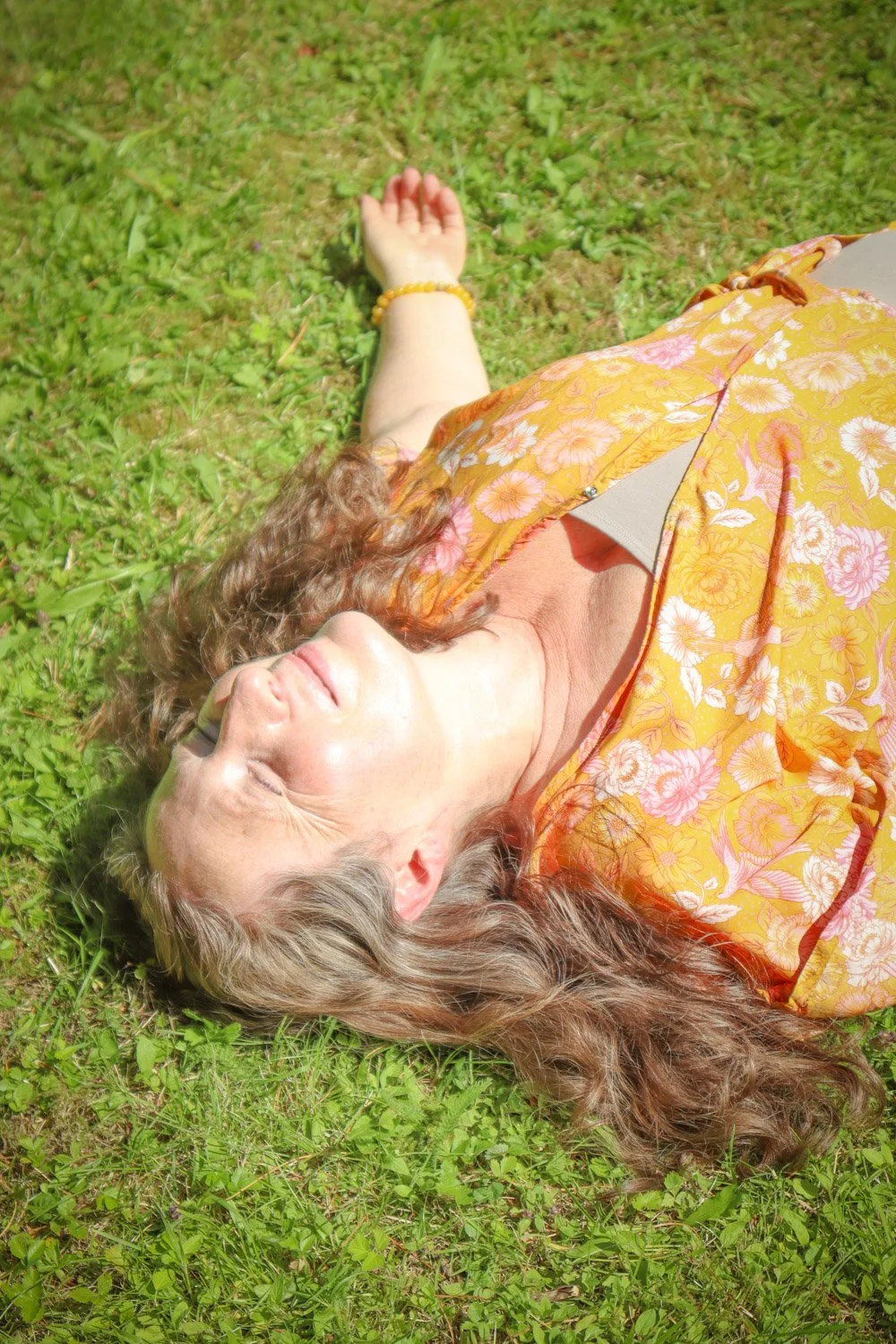 Kvinne gjør avspenningsøvelse i hagen. Opplev hvile, ro og lad batteriene med frisk luft og fredfulle omgivelser.