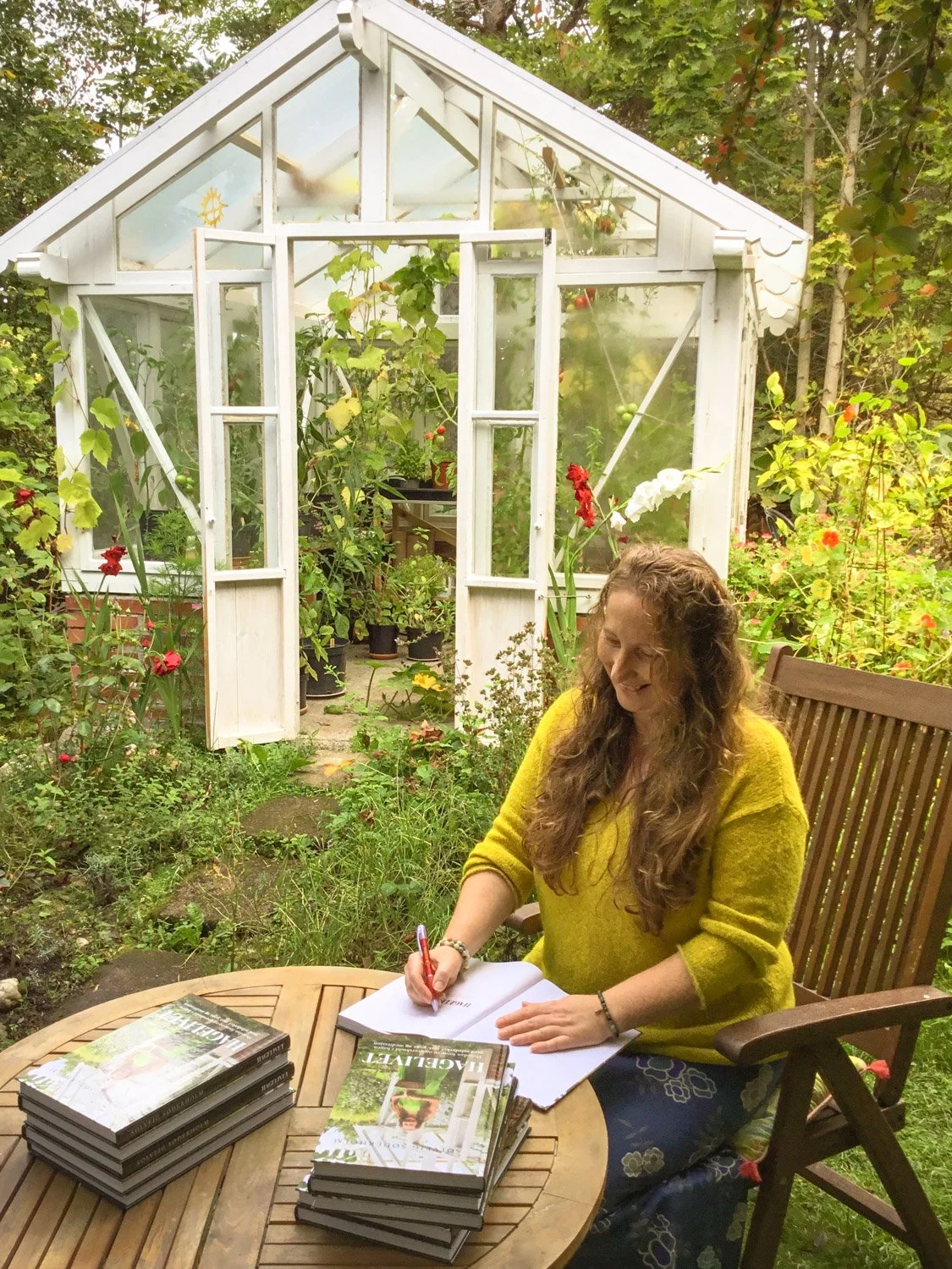 Forfatter Solveig Søderholm signerer boken Hagelivet i hagen foran drivhuset