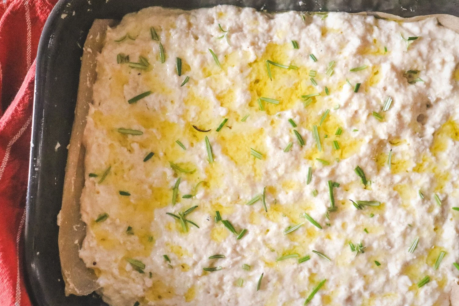 Glutenfri focaccia i form med olivenolje og flaksalt før steking