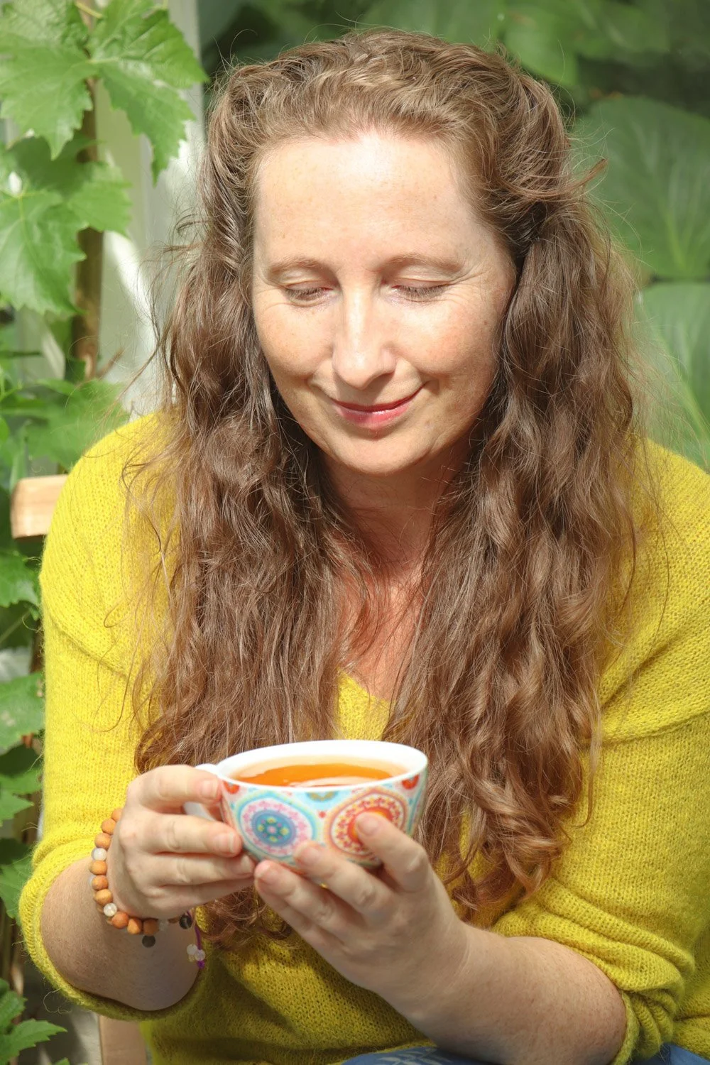 Kvinne holder en tekopp i drivhuset og slapper av, nyter ro, harmoni og mindfulness
