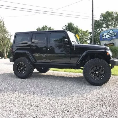 Blacked out Jeep Wrangler that is lifted with off-road wheels and tires. Tinted windows. 