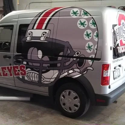Custom full vehicle wrap on Ford Transit van with OSU Buckeyes helmets and logos.