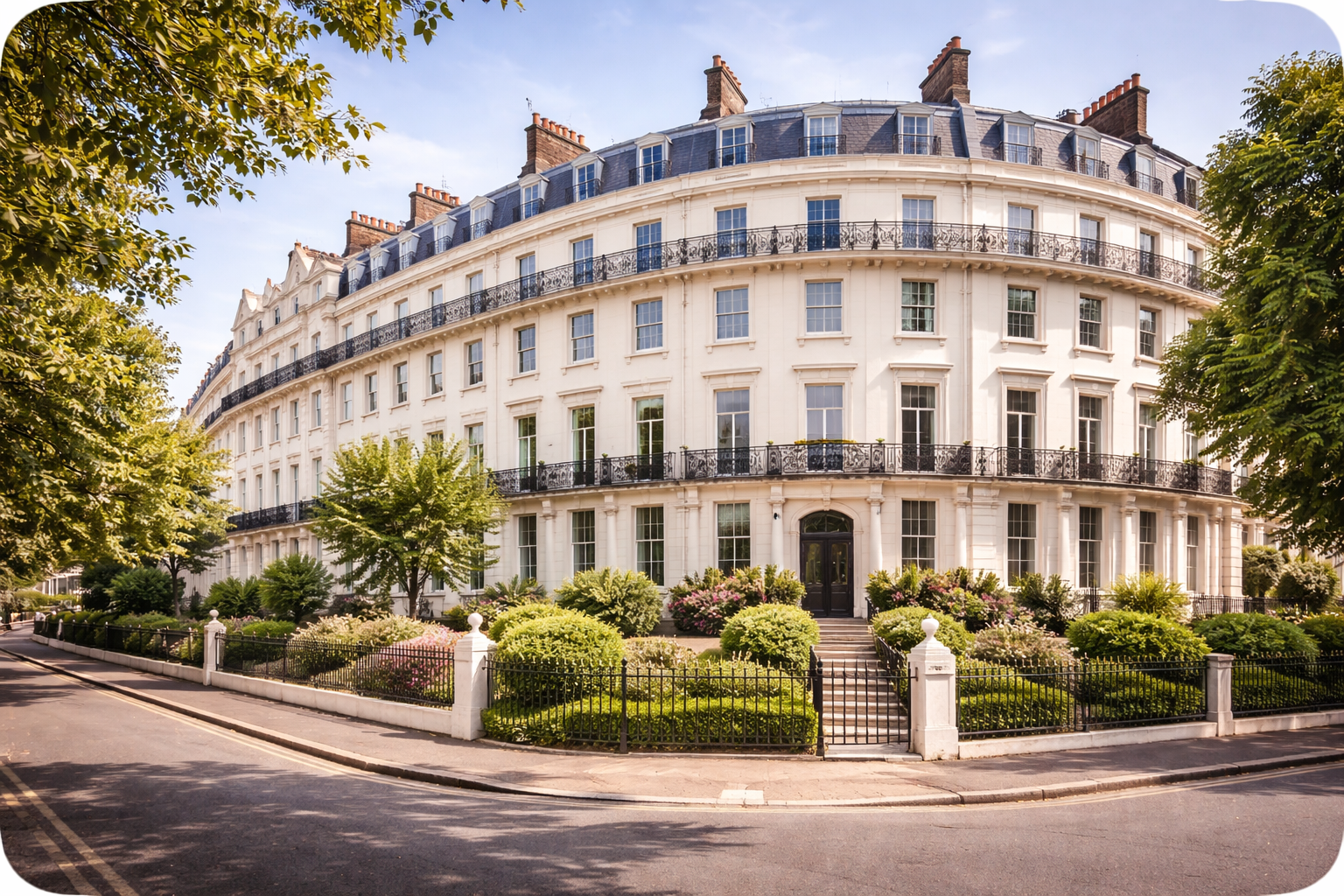 A large, white, curved apartment building with black balconies and multiple stories, surrounded by a garden with bushes and trees, on a sunny day.