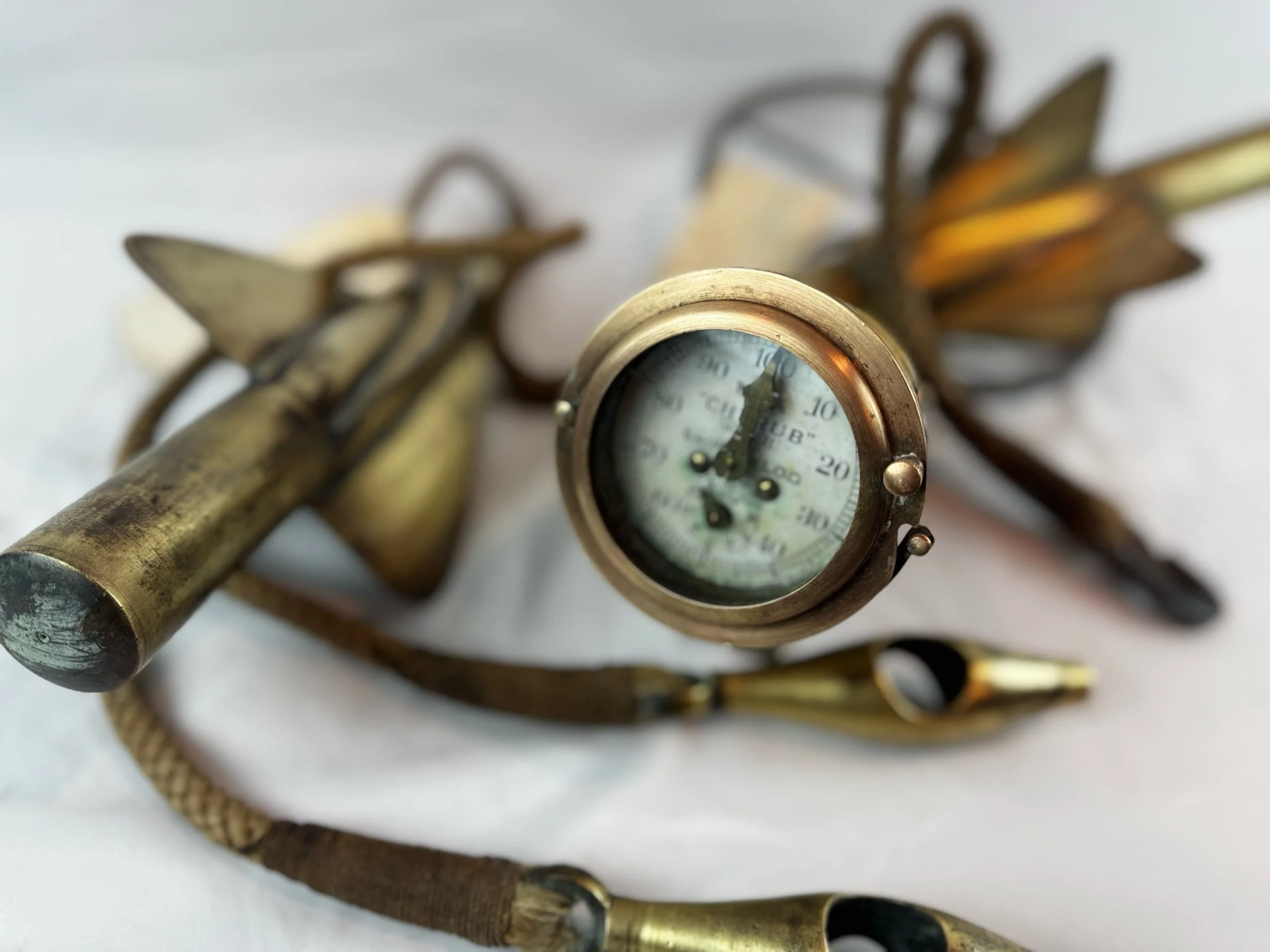 Close-up of vintage brass marine speedometer with a glass face, surrounded by brass propellers and implements to calibrate the speed in knots for a ship. 