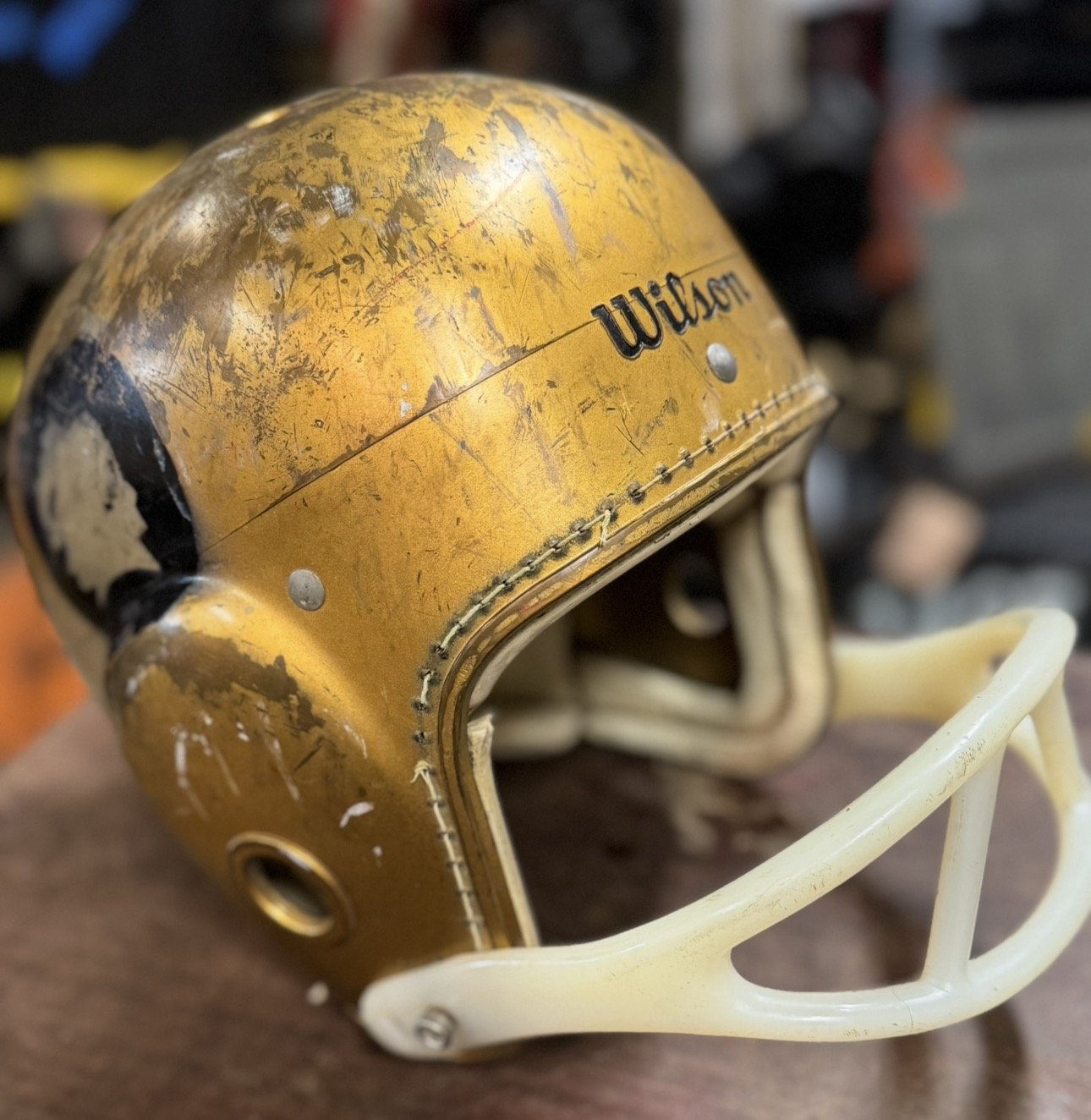 Used yellow football helmet with visible scratches and scuffs, Wilson logo, and white faceguard.