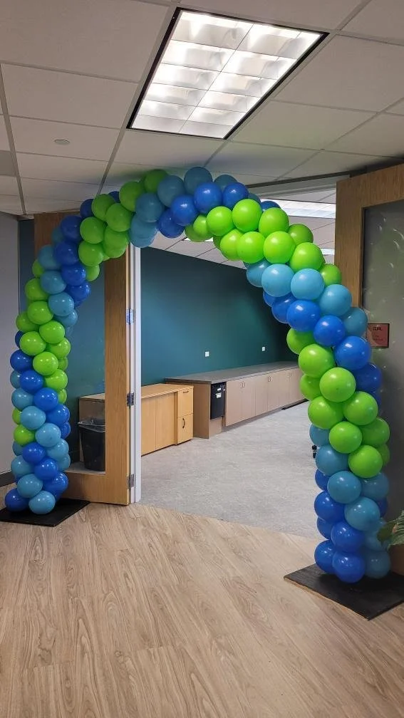 Balloon arch made of blue and green balloons at an office entrance.