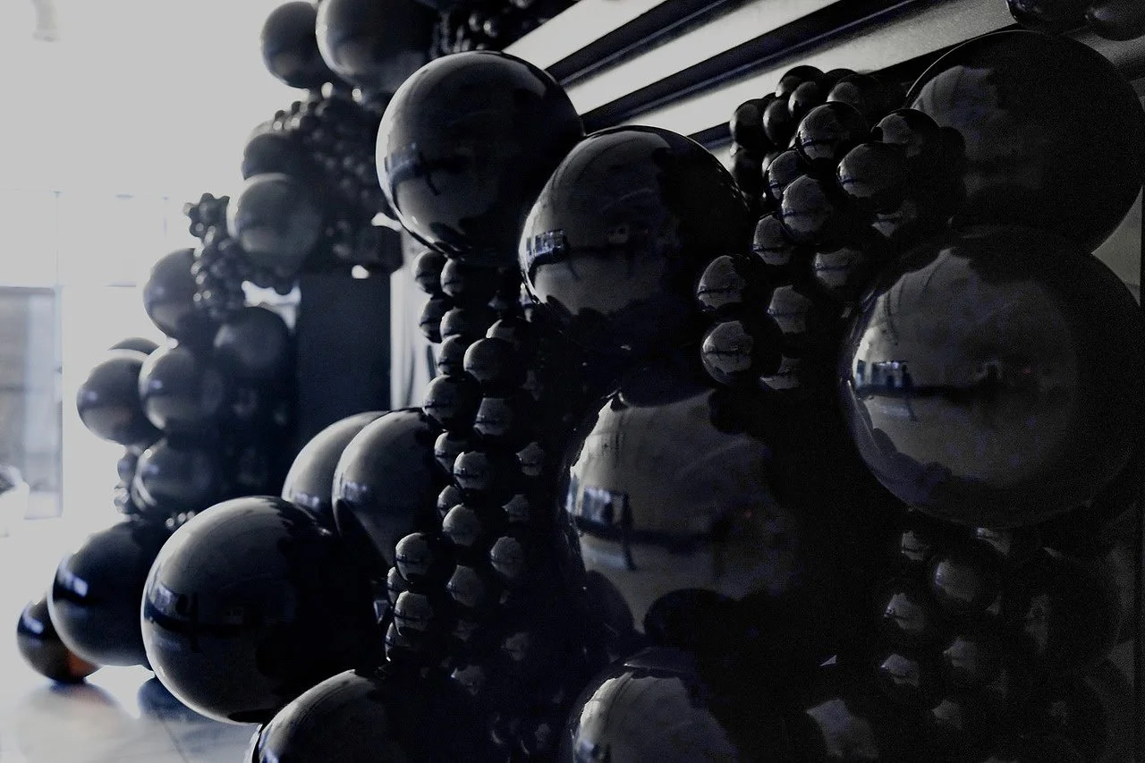 Close-up view of black soccer balls stored on shelves in a dimly lit room.