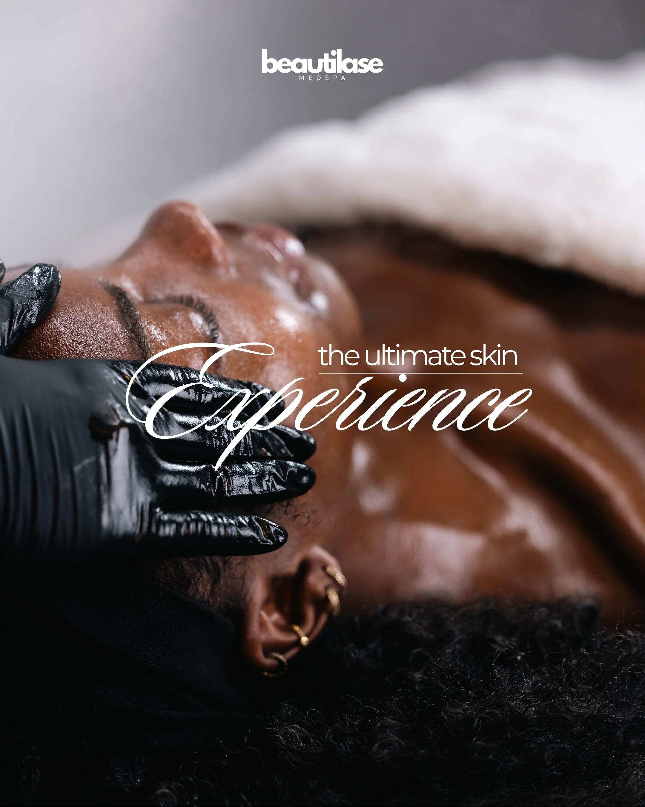 Close-up of a woman receiving a facial treatment in a spa, with her eyes closed and a towel wrapped around her head.