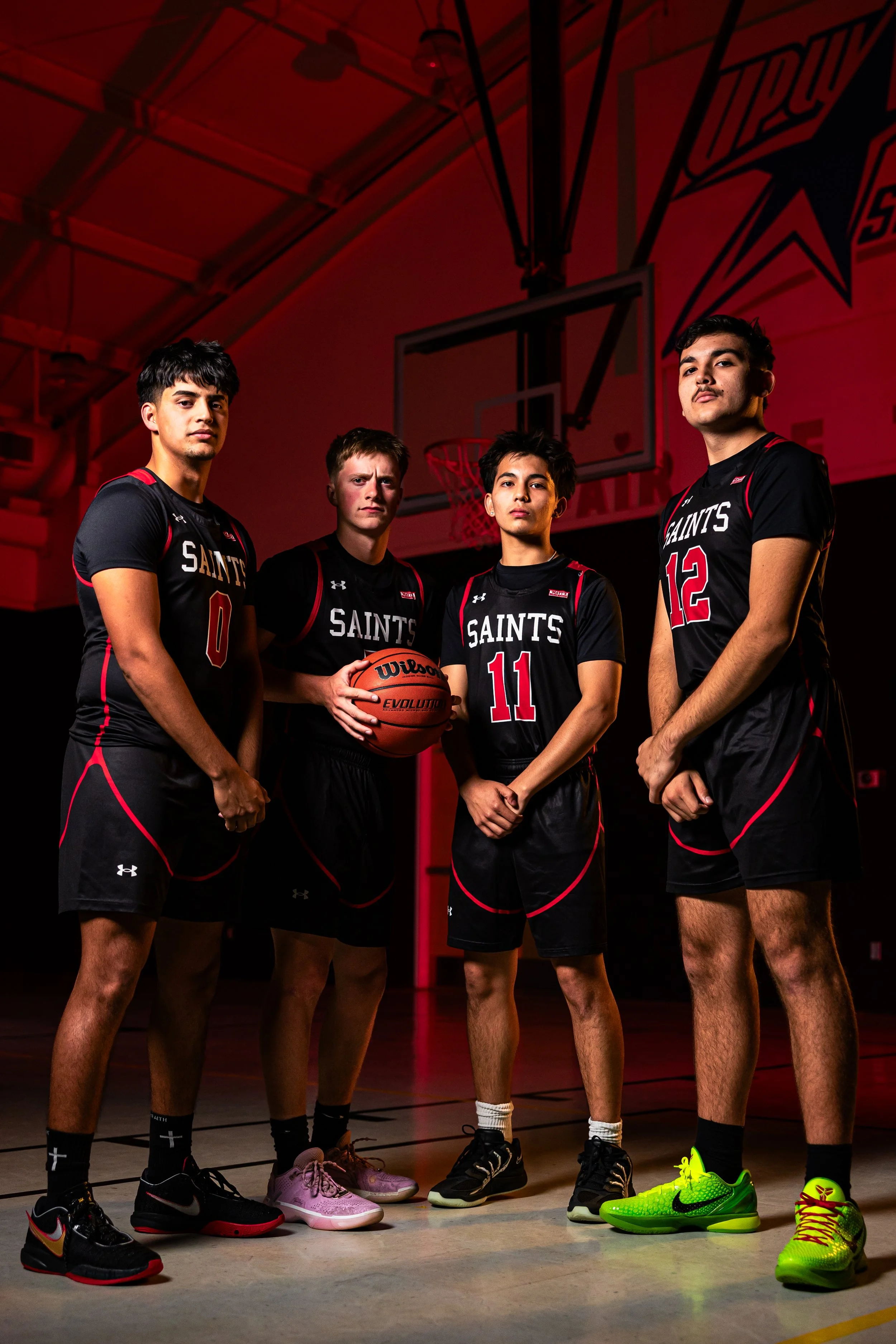 Four young men wearing black and red basketball jerseys with 