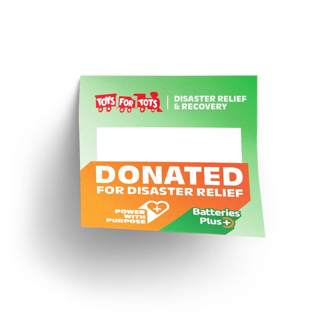 A donation card from Toys for Tots with green and orange colors, indicating it is donated for disaster relief, featuring icons and text about batteries and purpose.
