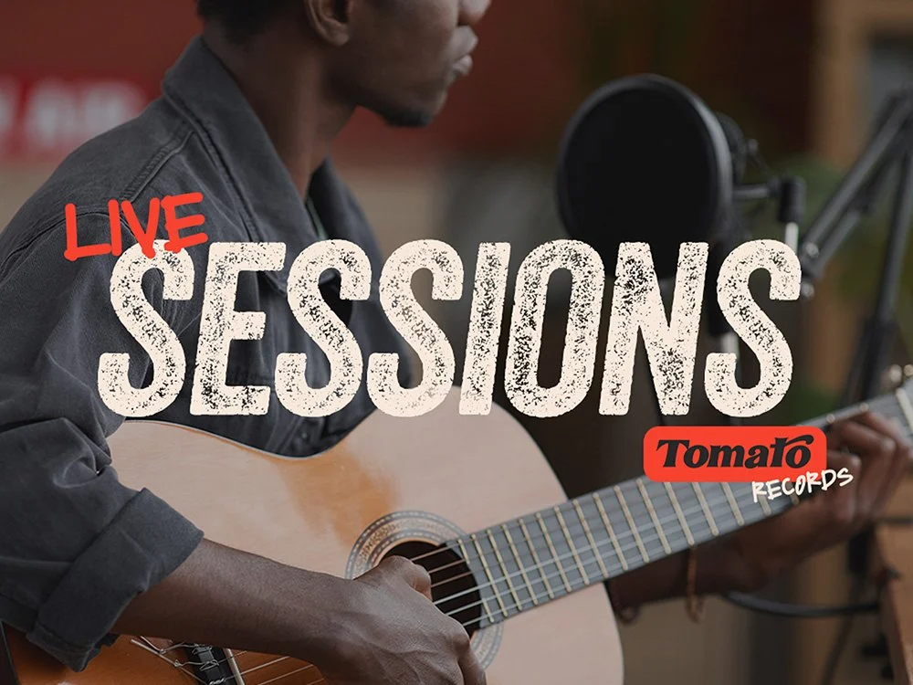 A person playing an acoustic guitar with a microphone set up in front of them, promoting live music sessions at Tomato Records.