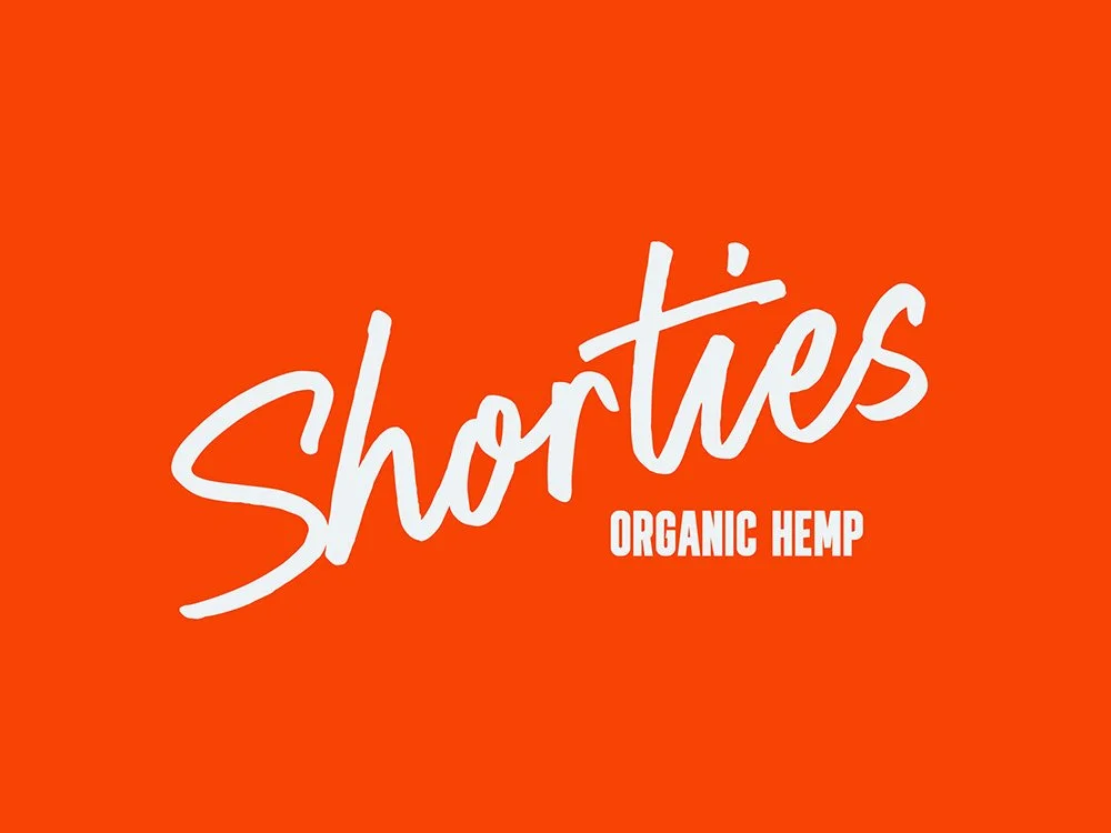 Logo for Shorties Organic Hemp, with the word "Shorties" in large, white, cursive font and "Organic Hemp" in smaller, white, block letters on an orange background.