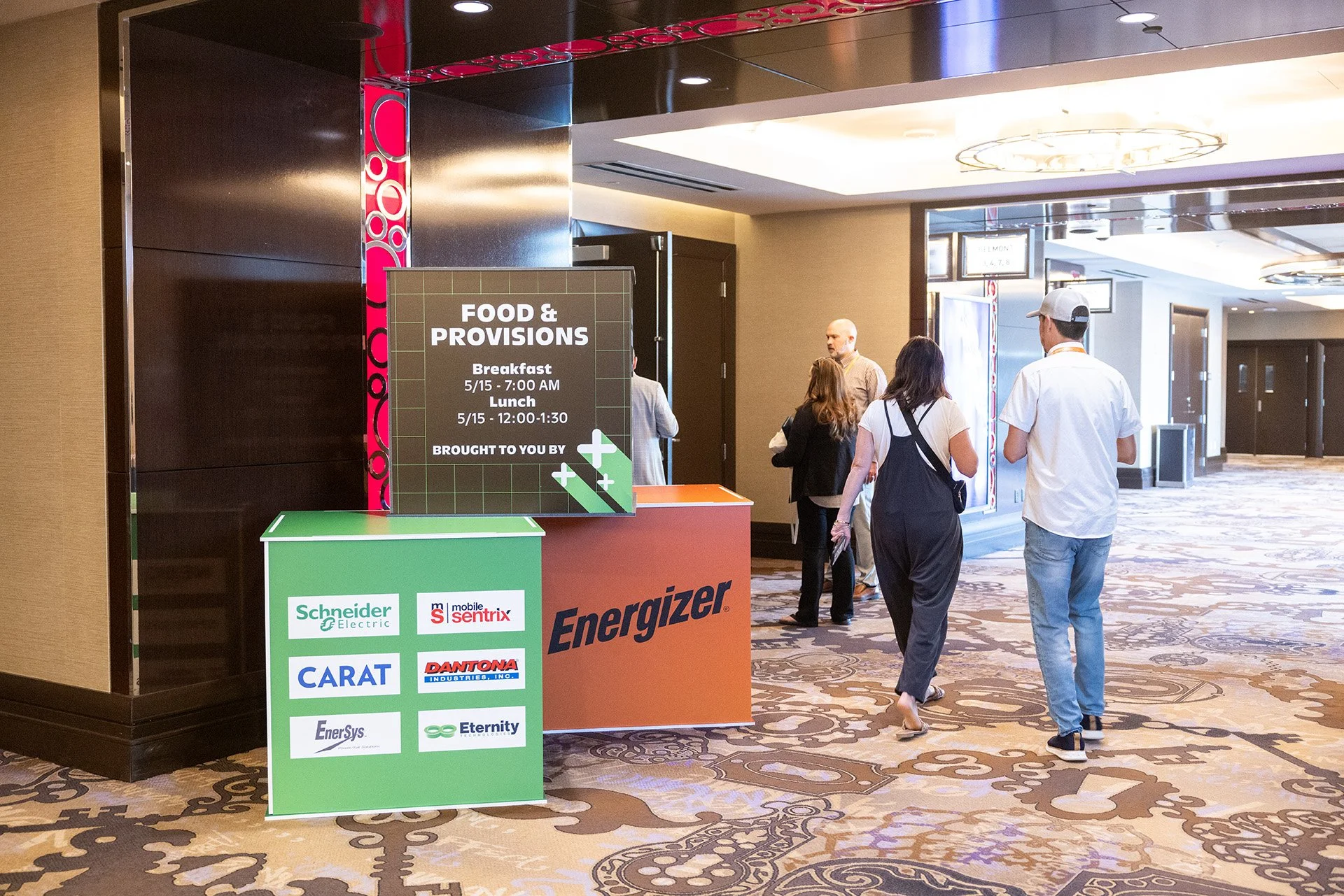 People walking in a hallway near food and provisions sign at a conference or hotel