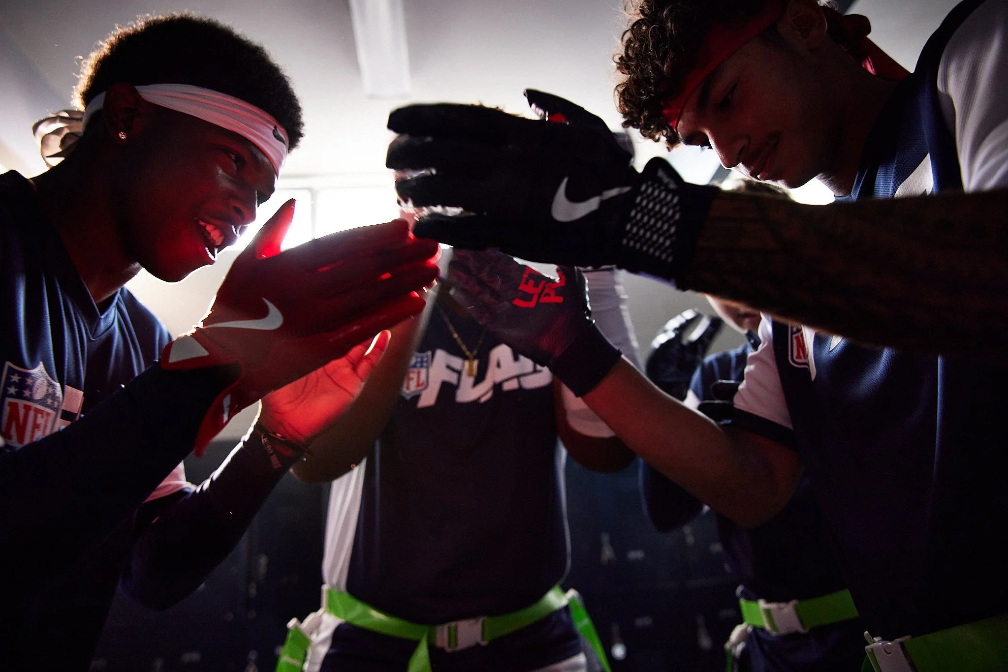 Football players in NFL uniforms giving each other high fives in a locker room.