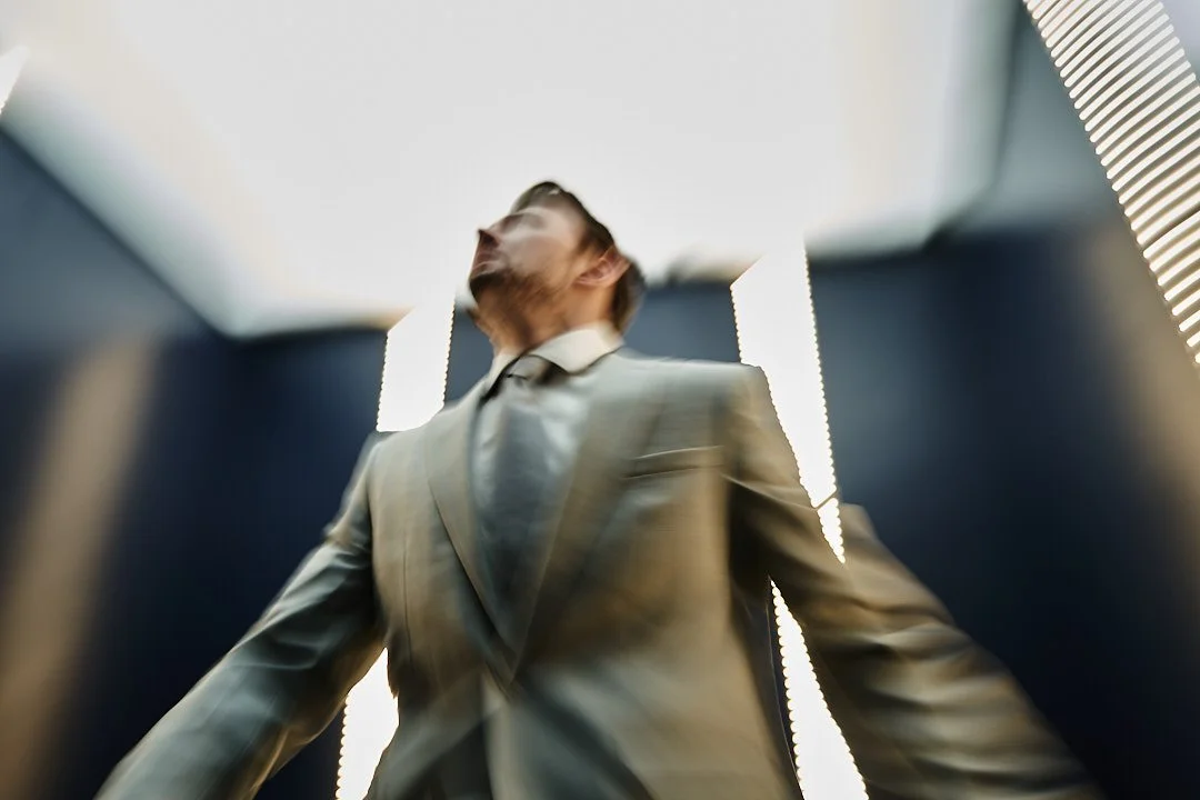 A man wearing a suit in an elevator, viewed from below with a low angle.