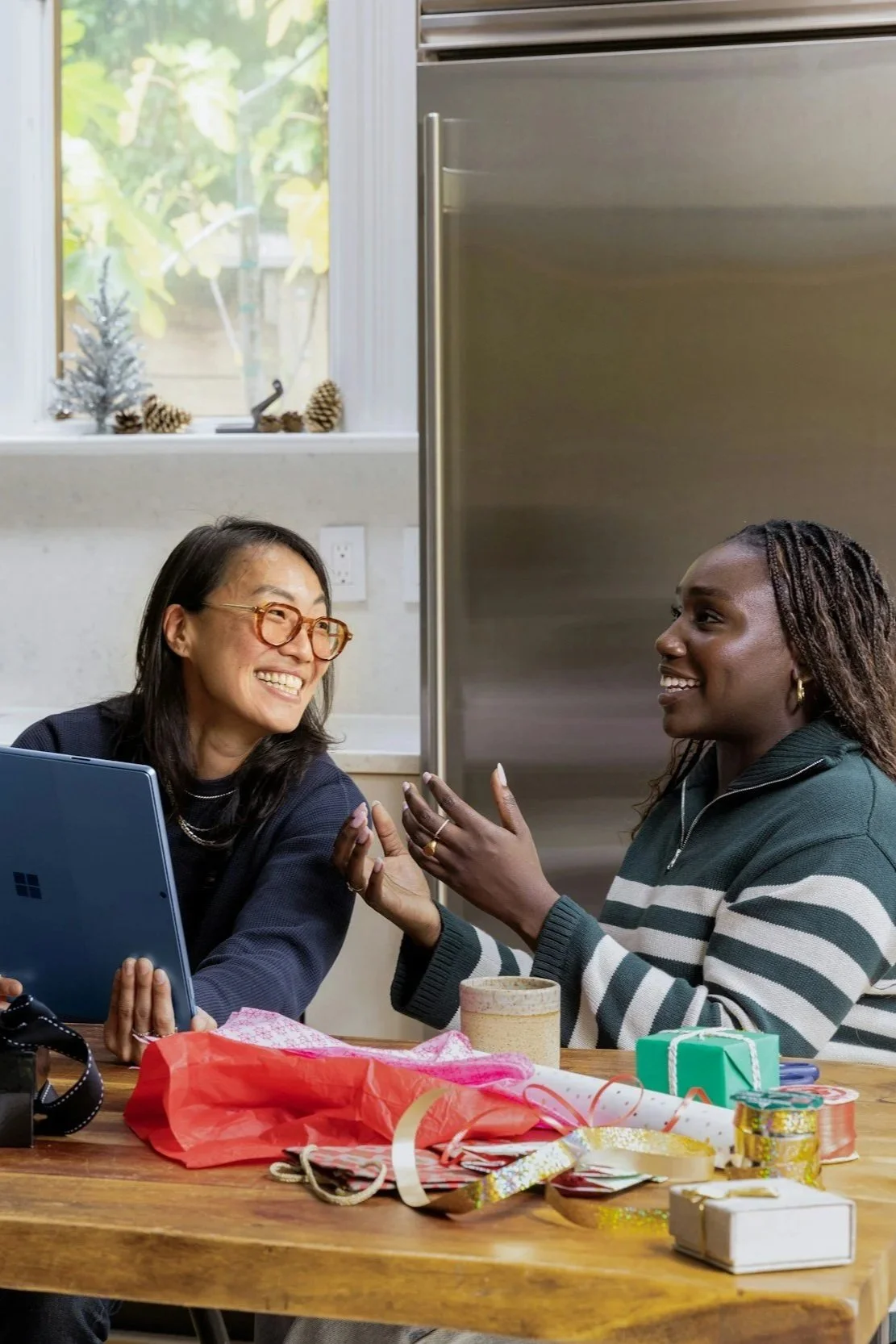 image of two women collaborating at a table sharing ideas. They have wrapping paper on the table as well as ribbon.