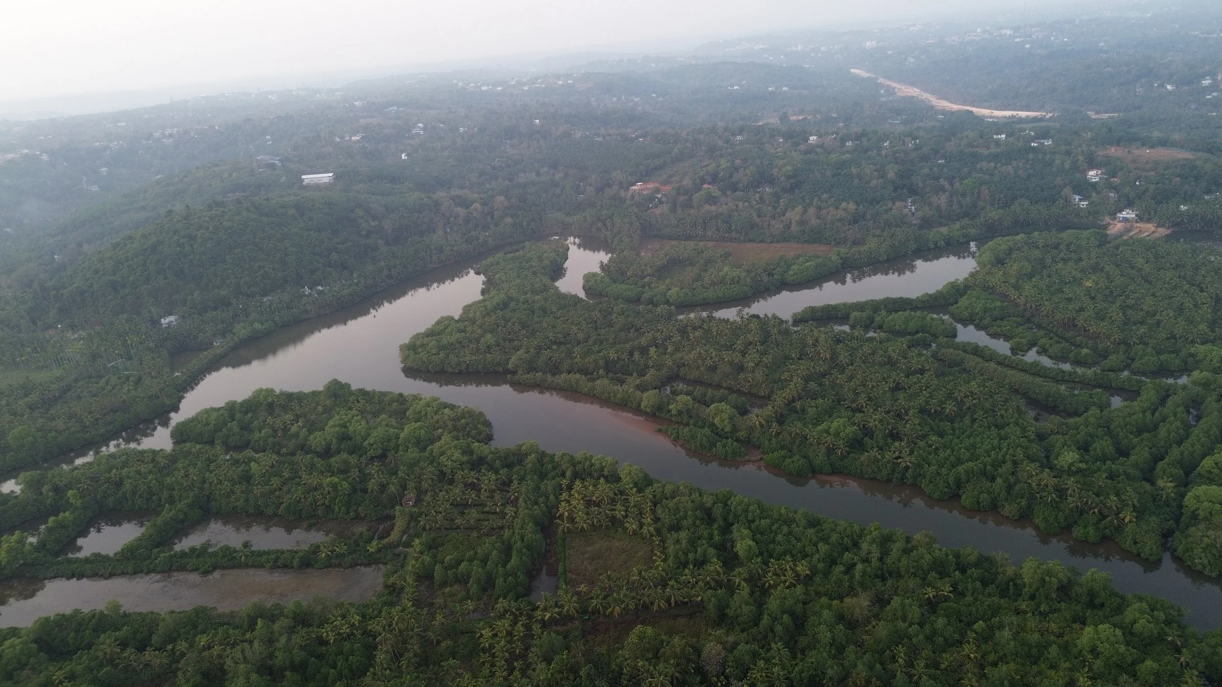 Aerial view of a lush green tropical landscape with multiple winding rivers and dense vegetation.
