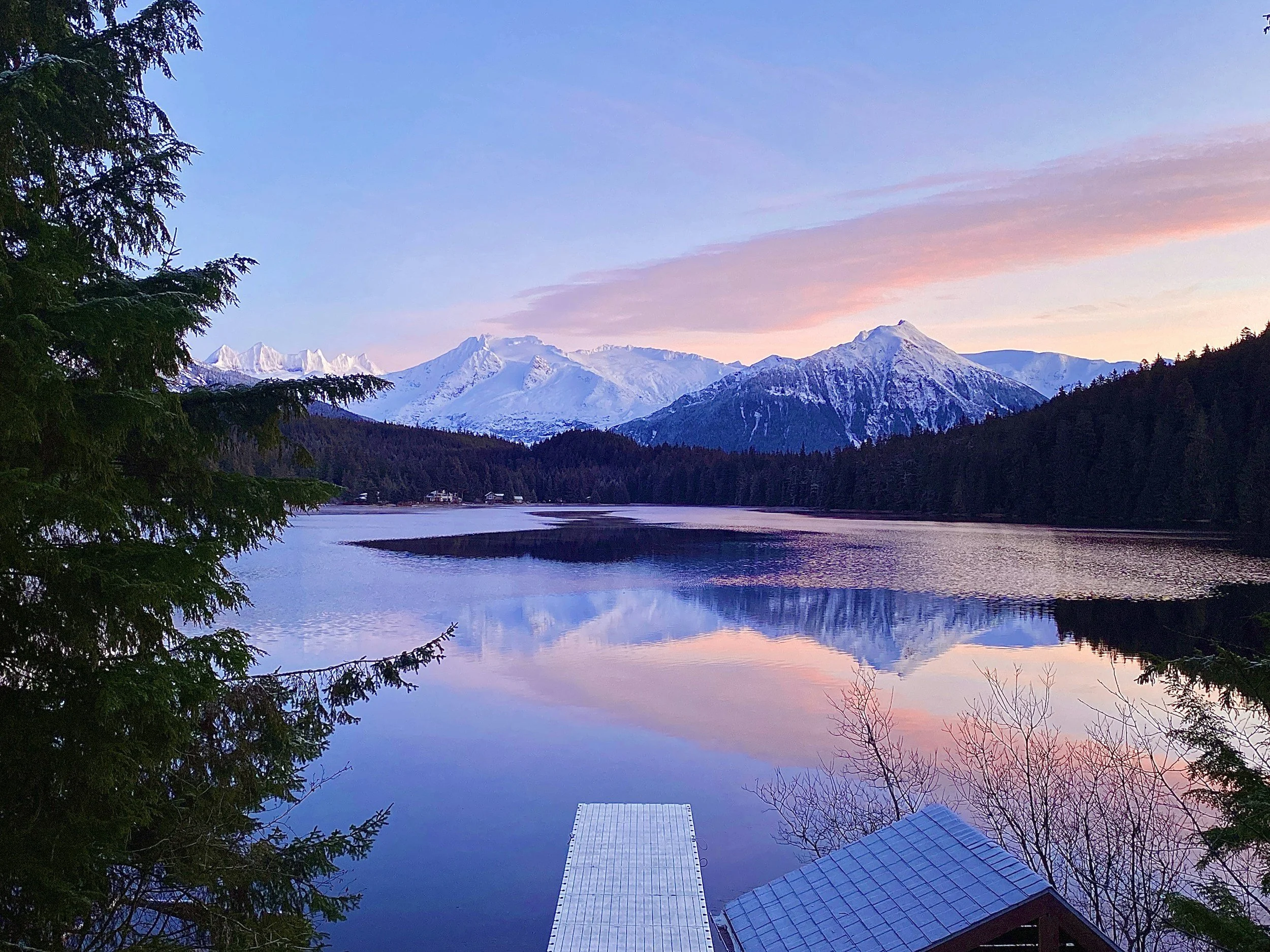 Calm summer landscape in Alaska with water and mountains, reflecting quiet grandeur and natural beauty.