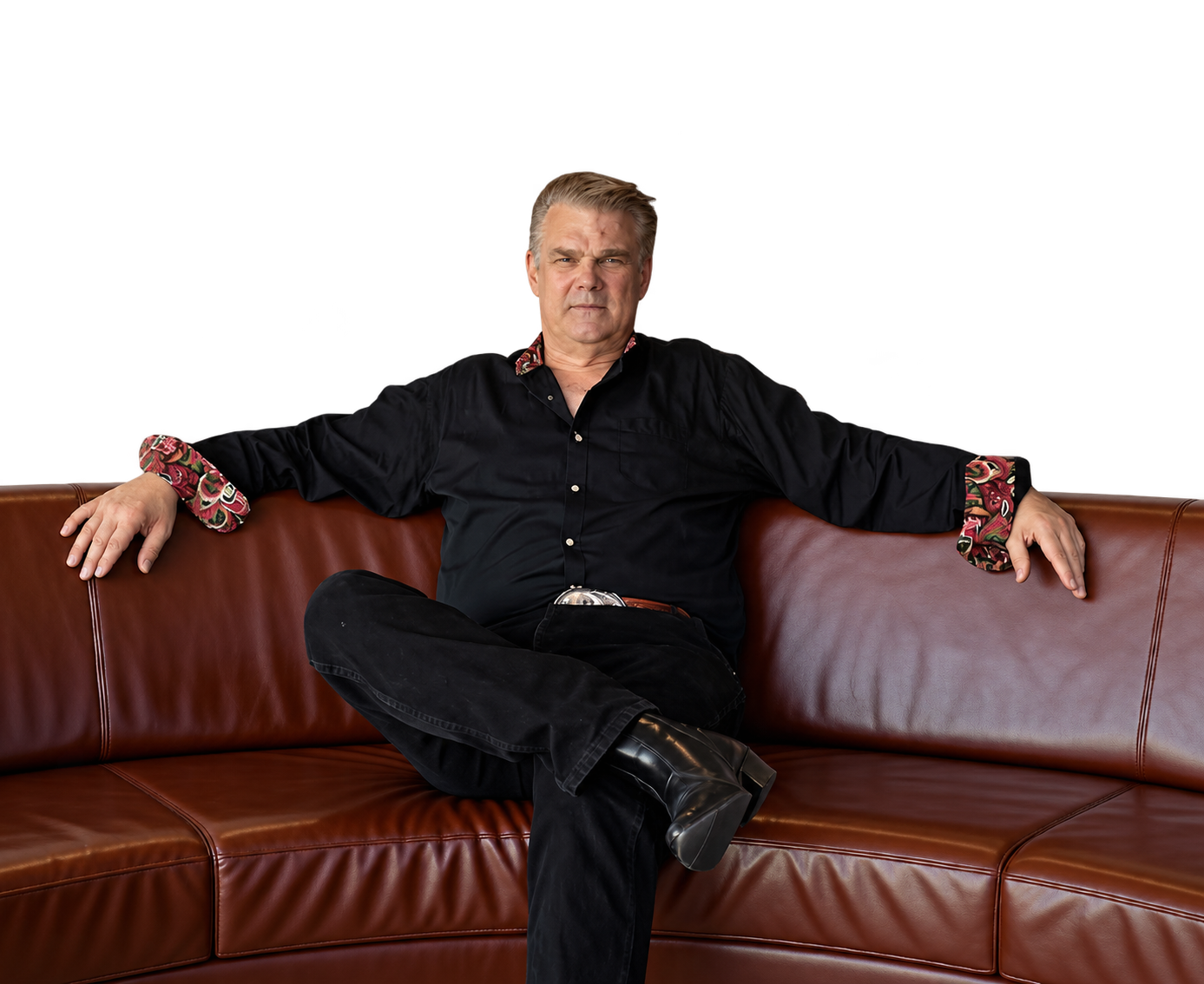 Sean Clarke seated confidently on a brown leather sofa.