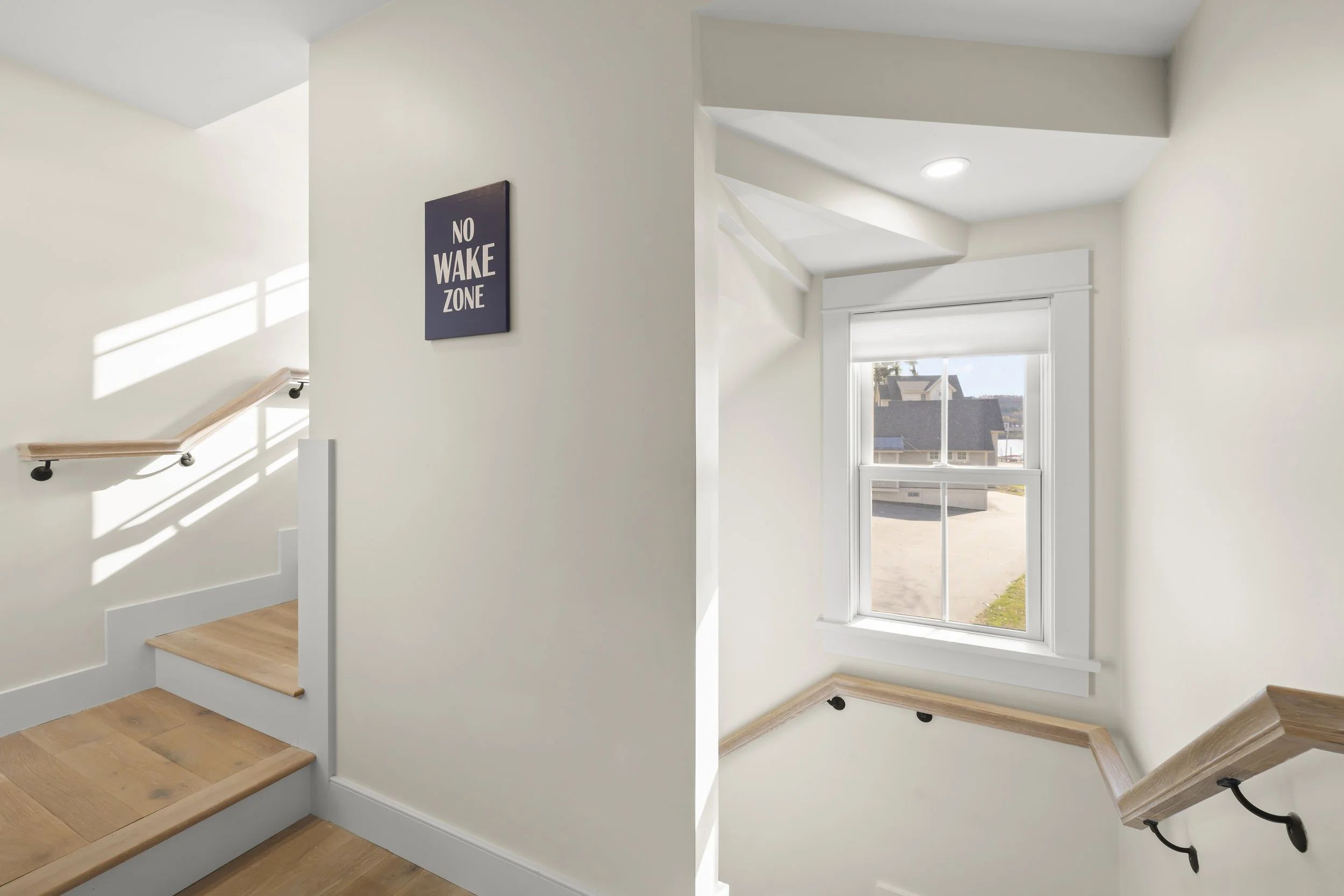 Interior view of a staircase landing with white walls, a window, and a 