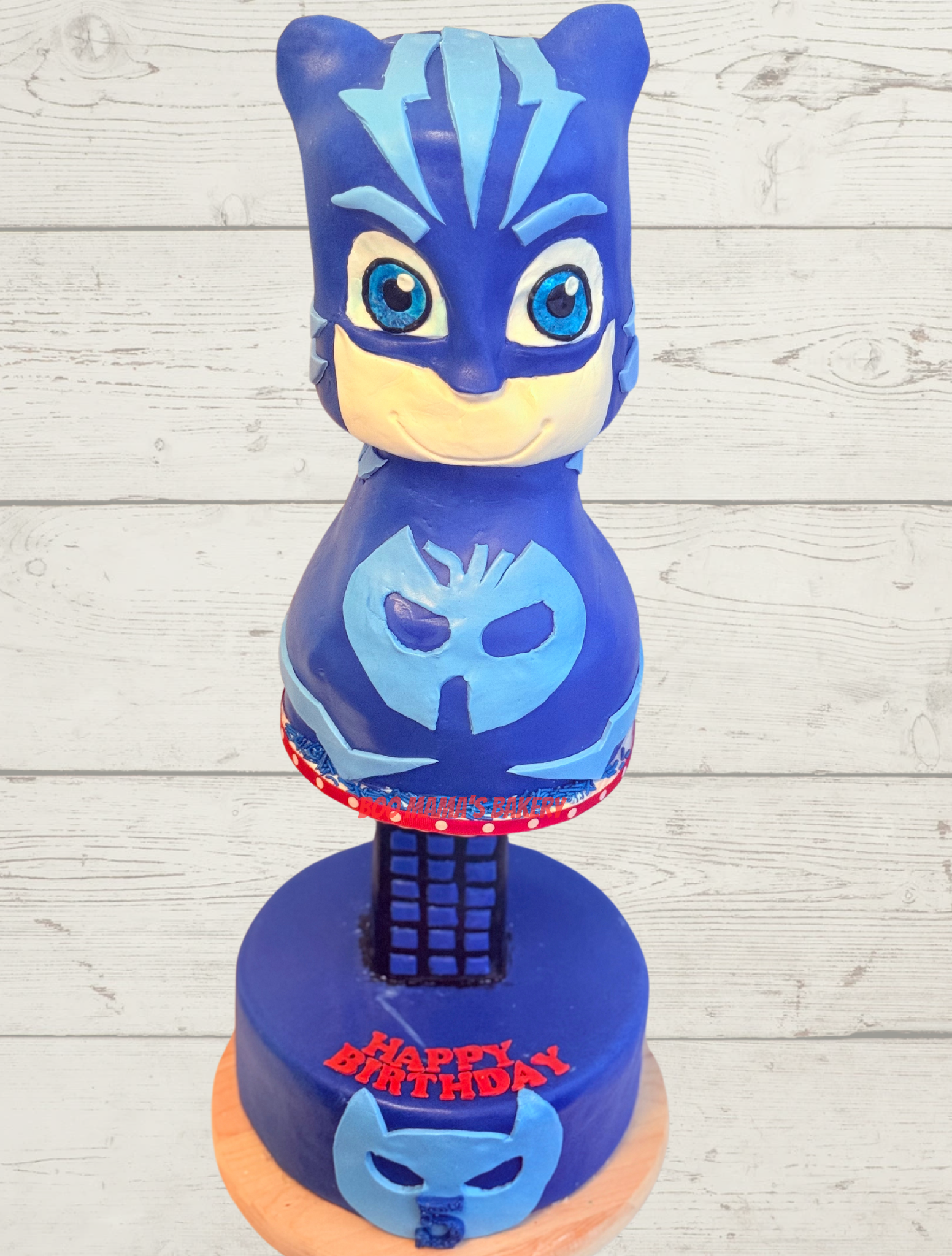 Blue Spider-Man themed birthday cake with character face, spider emblem, and 
