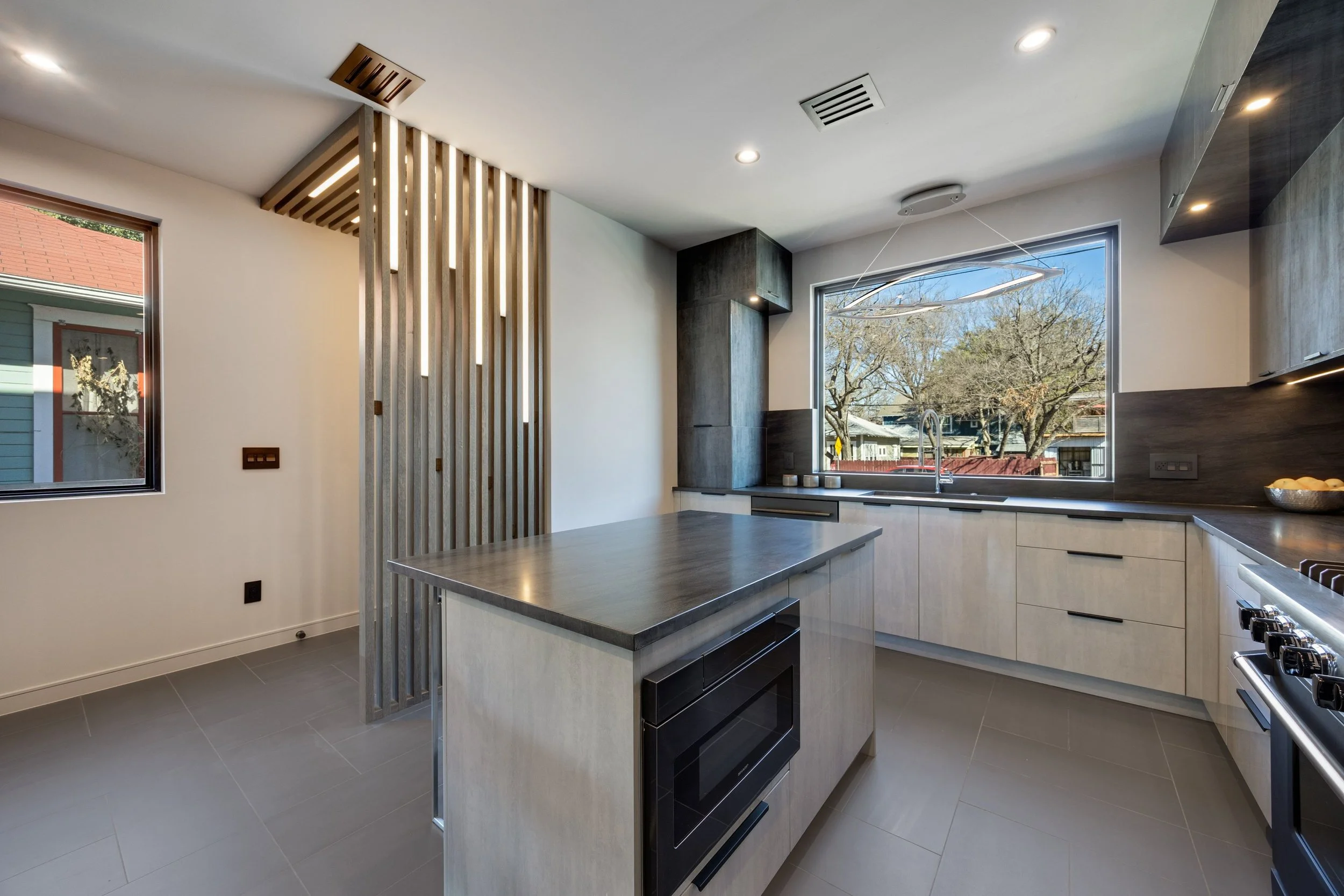 Modern kitchen with large window, island with microwave, and sleek cabinetry.