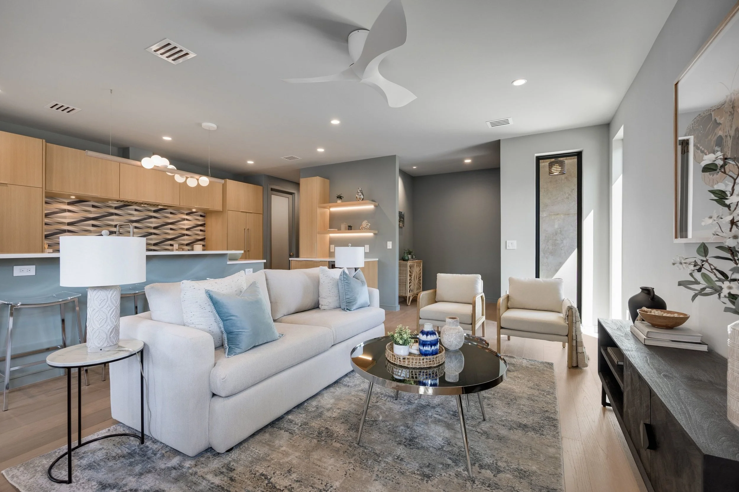 Modern living room with white sofa, accent chairs, black coffee table, and decorative items.