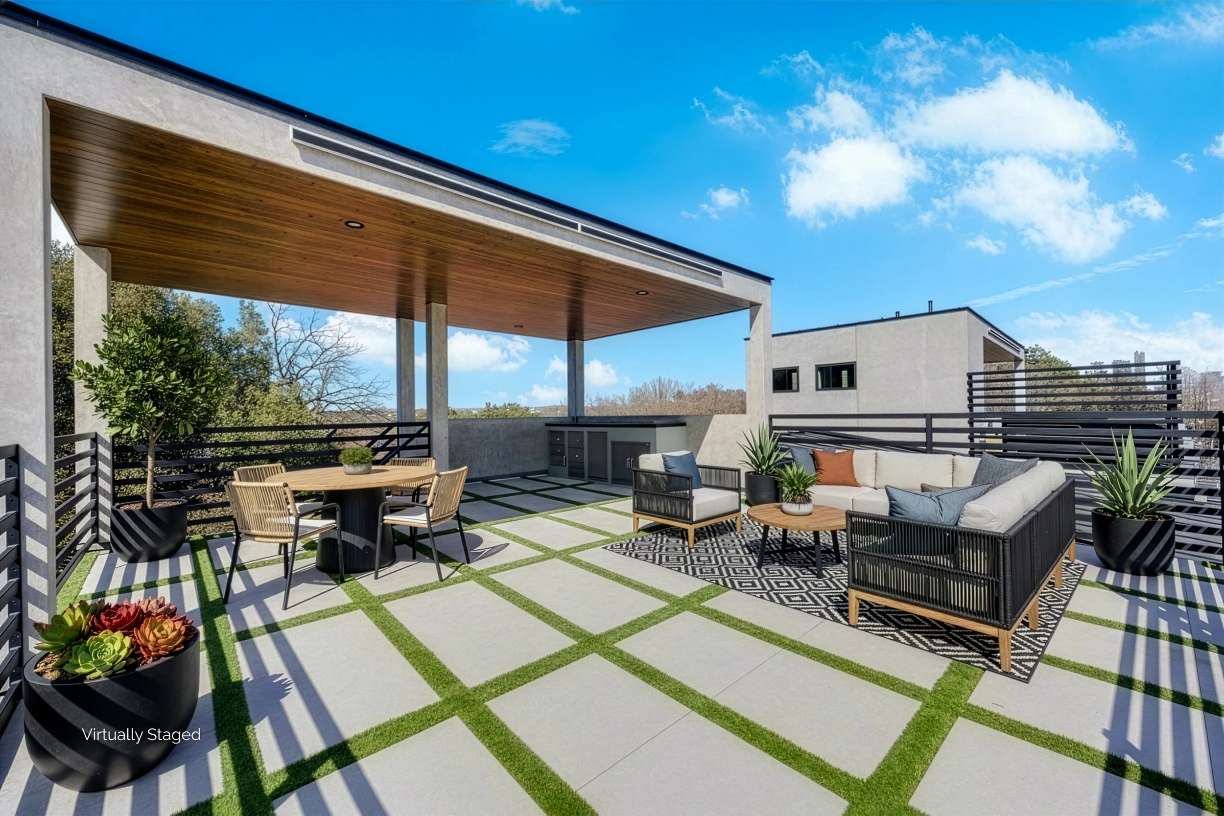 Modern outdoor rooftop patio with seating area, potted plants, and a shaded section, under a blue sky with clouds.
