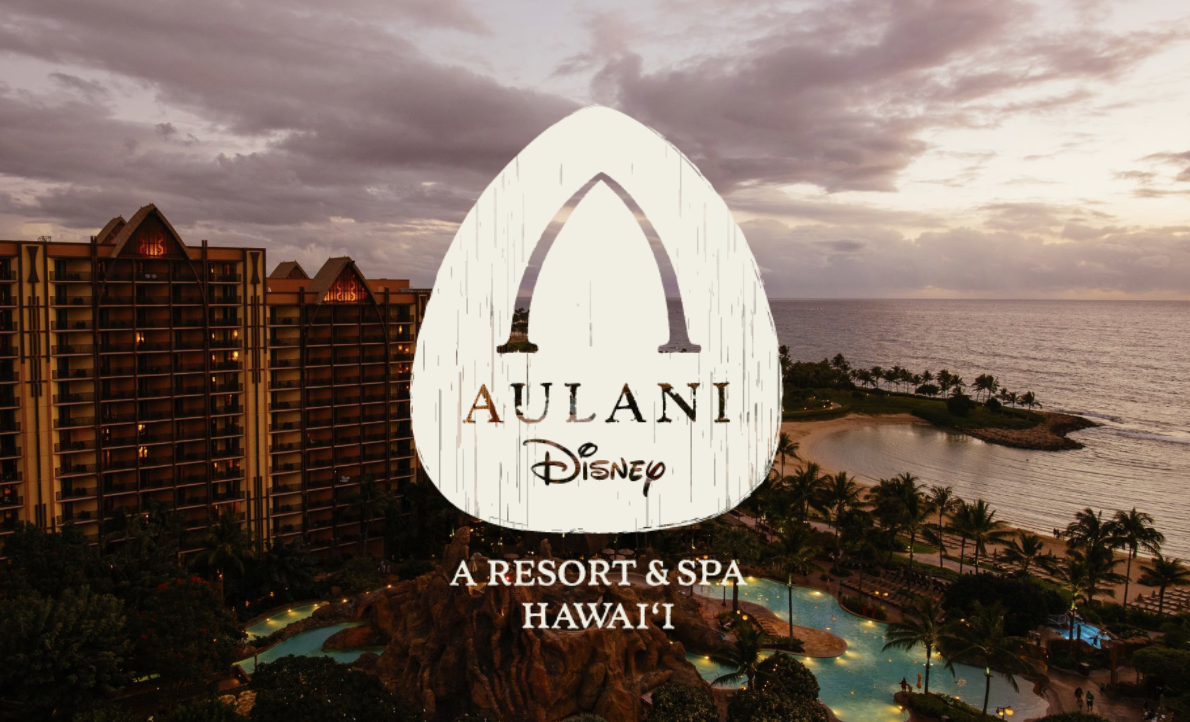 Aerial view of Aulani, a Disney Resort & Spa in Hawaii, during sunset, with the ocean, sandy beach, palm trees, and hotel buildings visible.